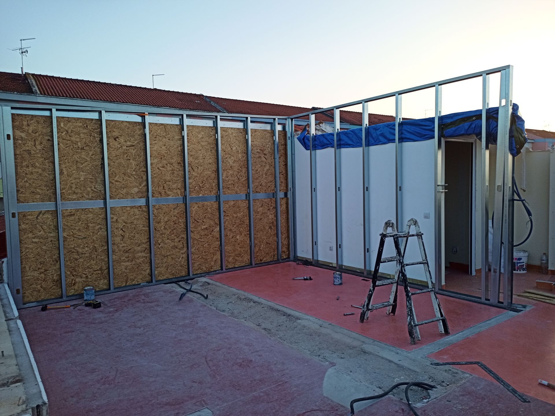 Estrutura metálica de paredes em construção, com placas de isolamento, em um terraço na cobertura.