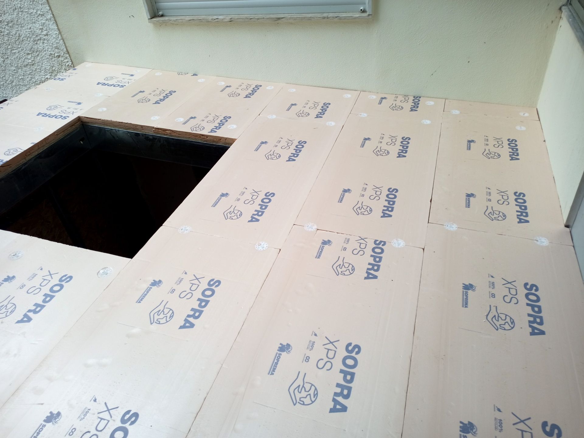 Painéis de isolamento de piso colocados sobre uma superfície com abertura quadrada. Painéis de espuma bege com a etiqueta 