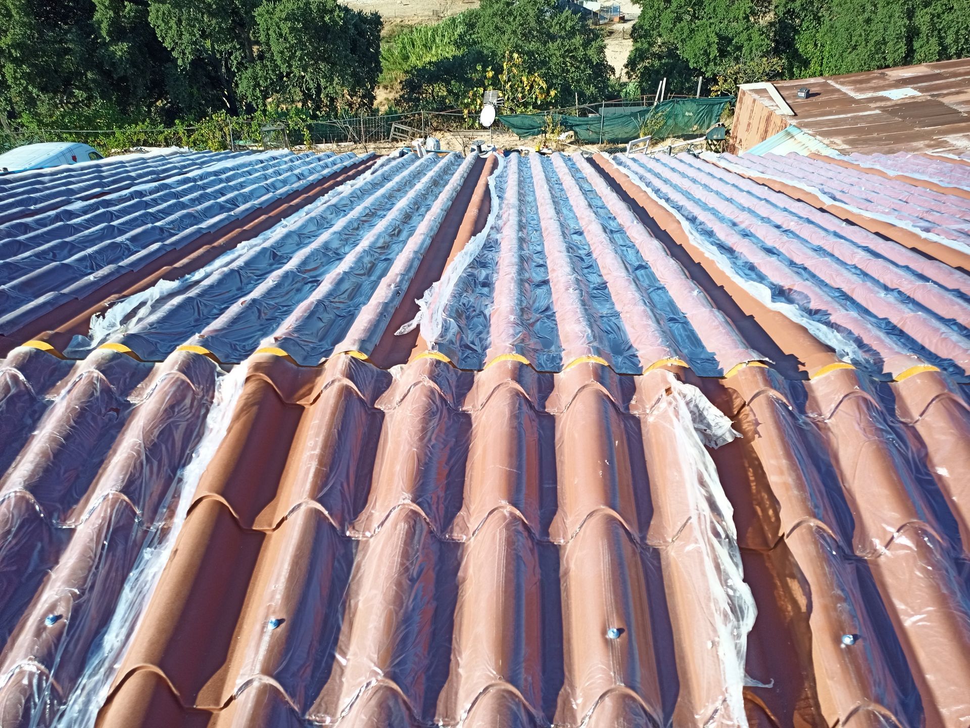 Telhado de telhas marrons com seções revestidas de material prateado.