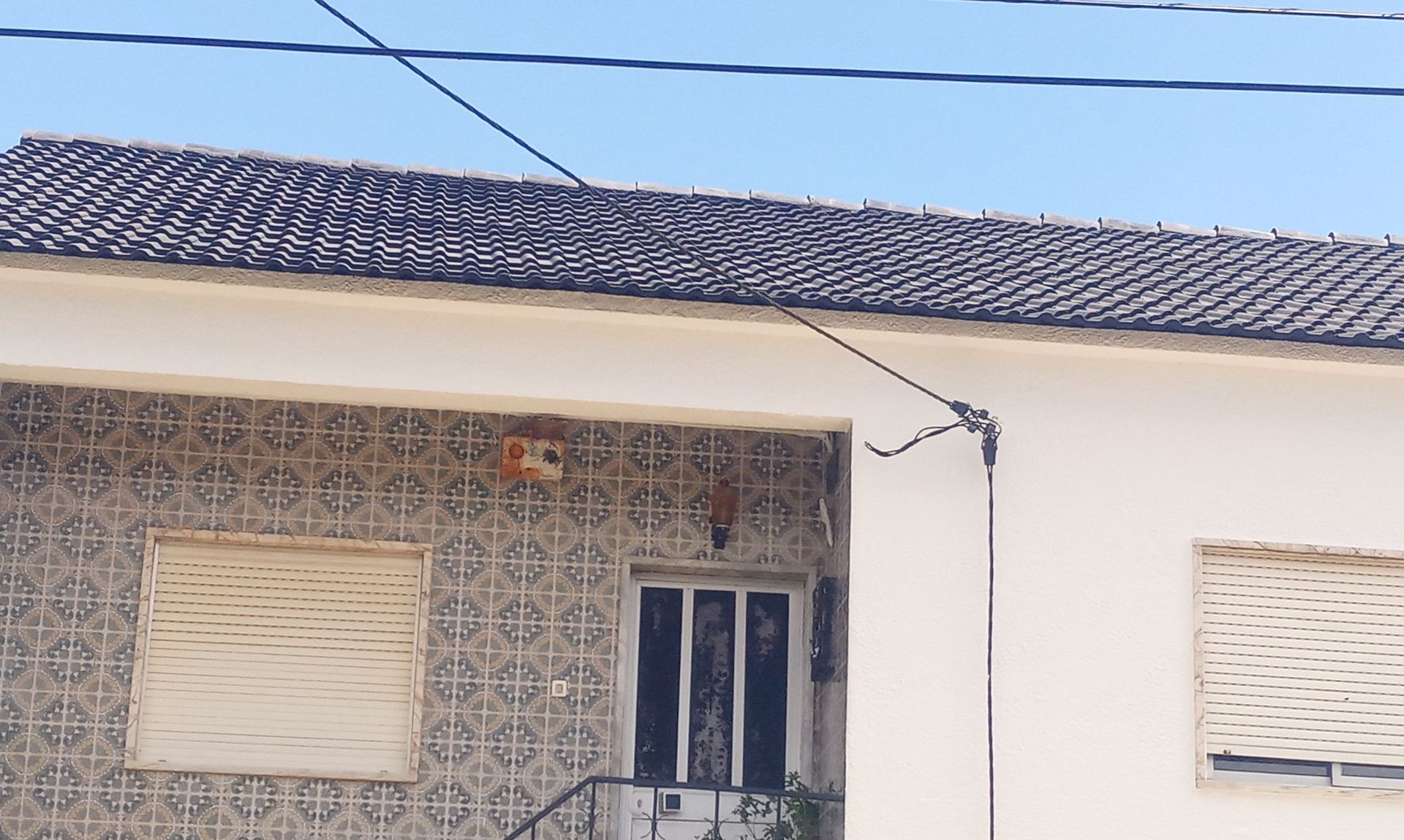 Exterior do edifício com fachada padronizada, telhado de telha e persianas fechadas.