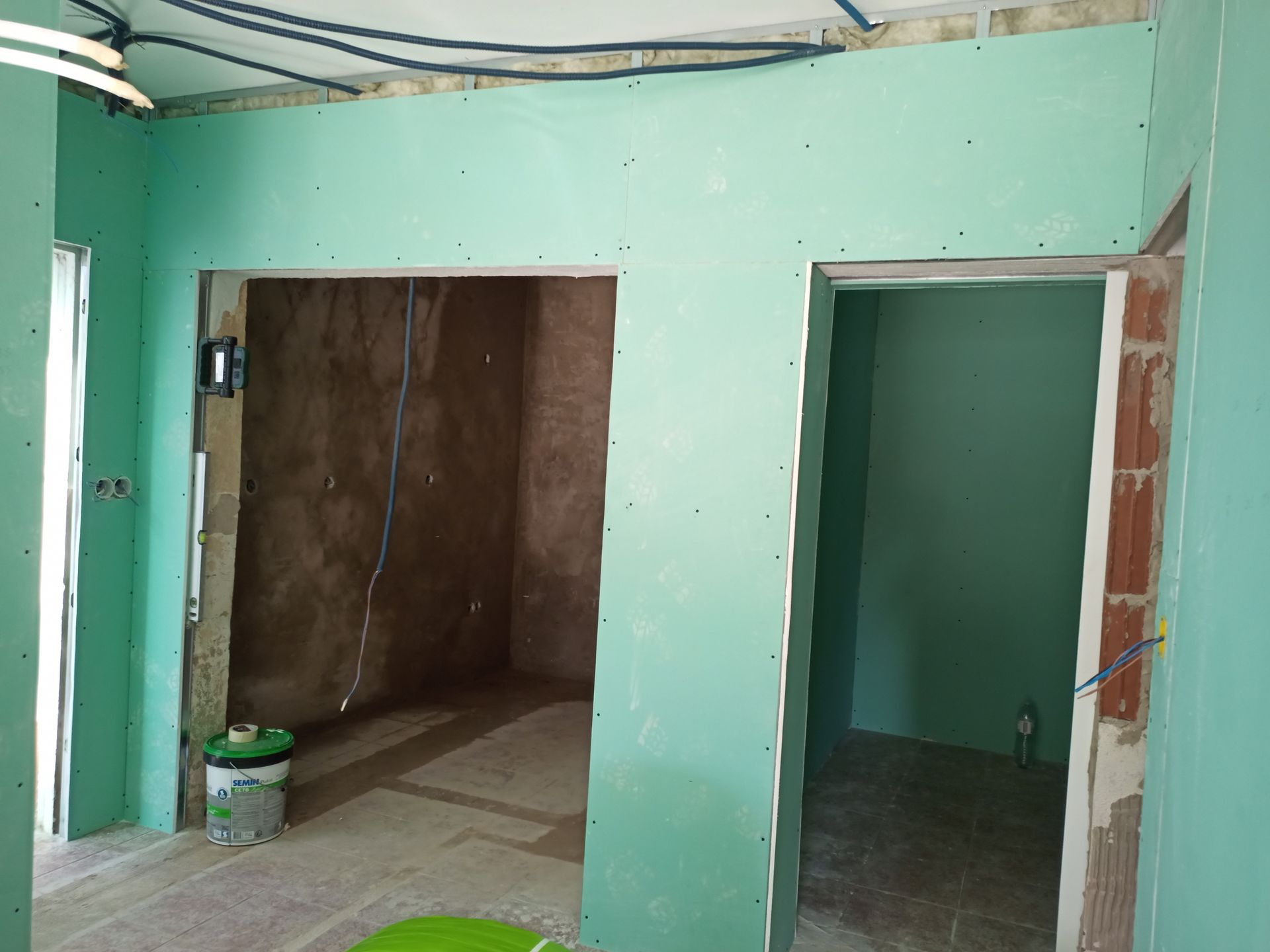 Interior com portas e drywall verde durante a construção.