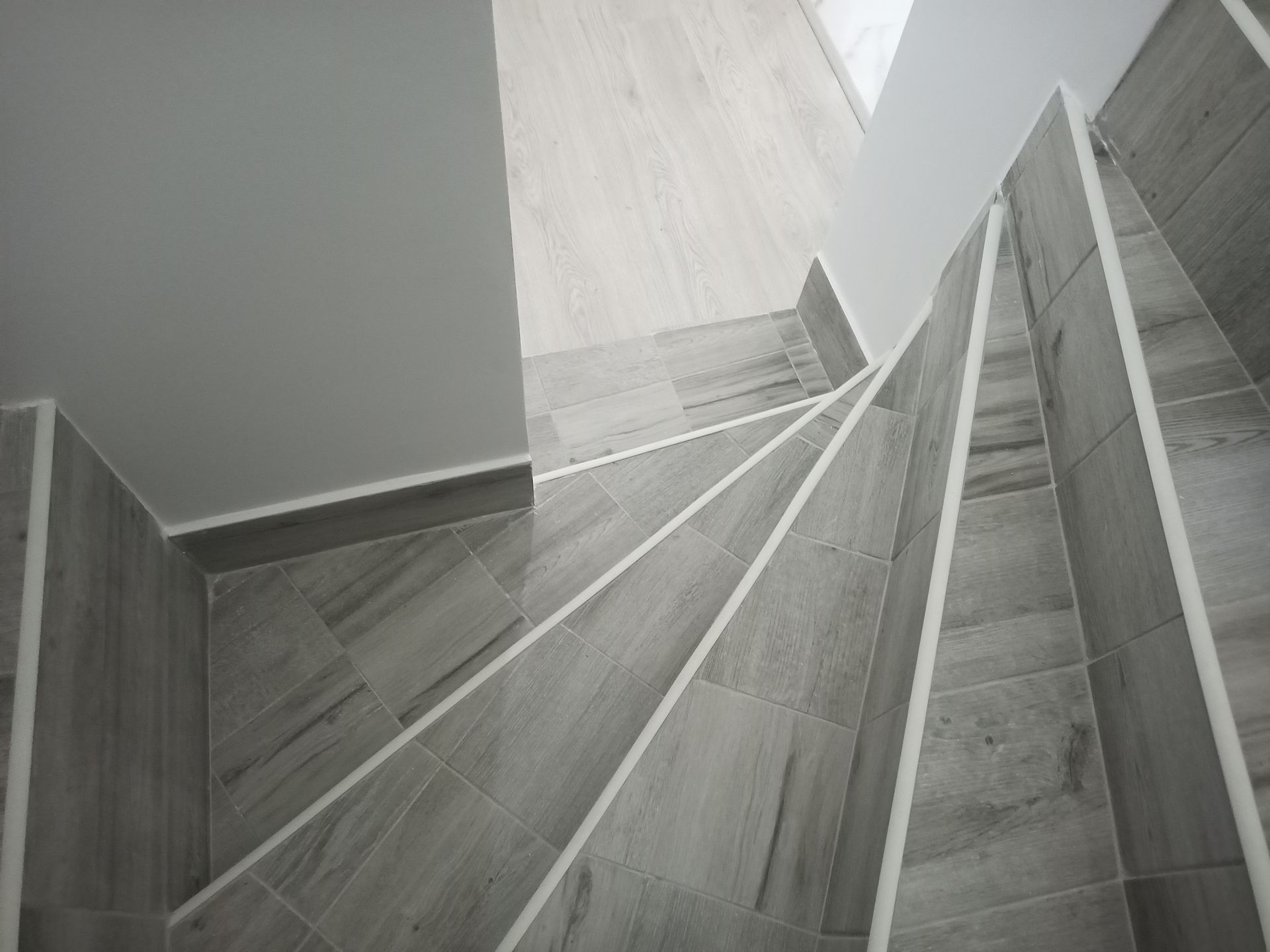 Escada em espiral com azulejos cinza e detalhes em branco.