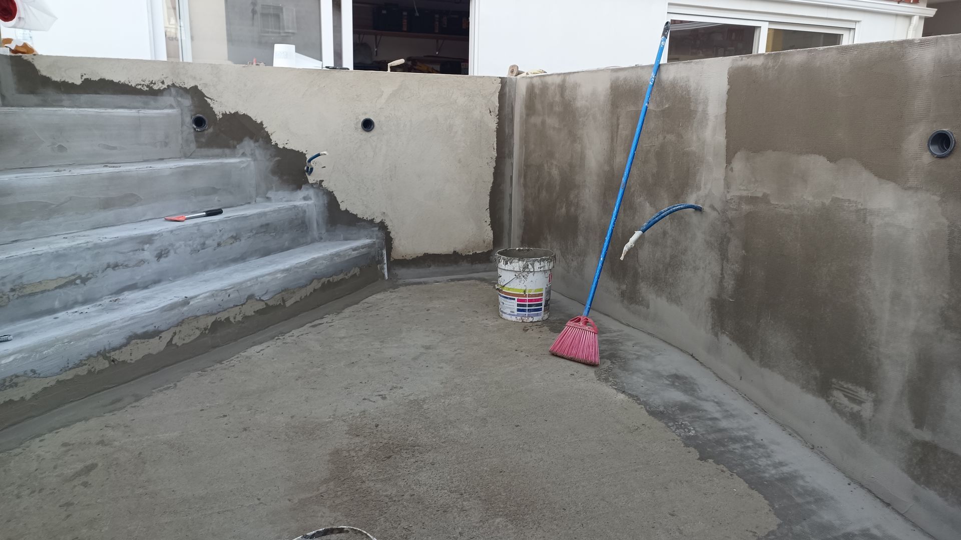 Piscina de concreto em construção, com degraus, paredes curvas e ferramentas.