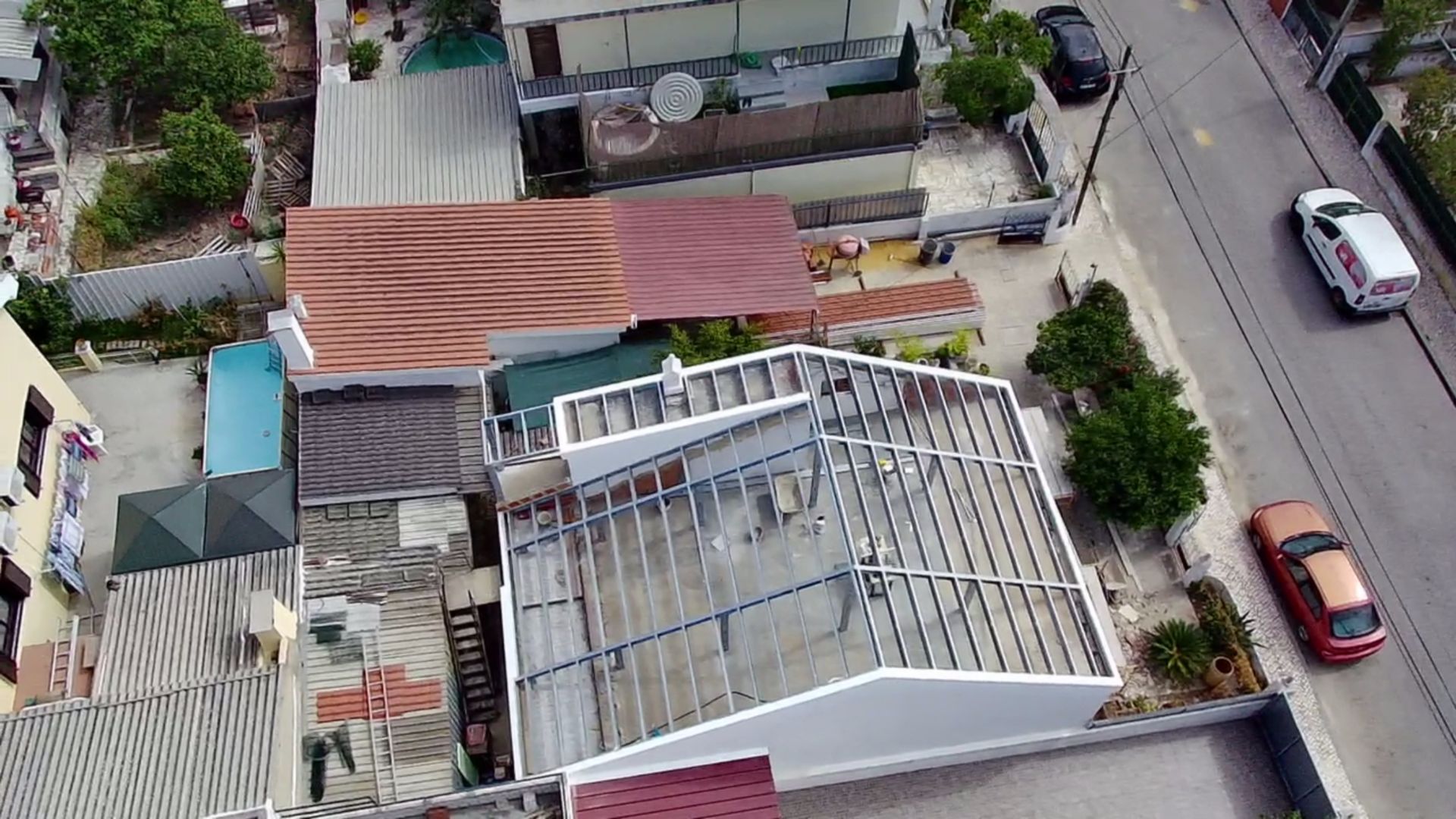 Vista aérea de edifícios com telhados de cores variadas perto de uma rua com carros.