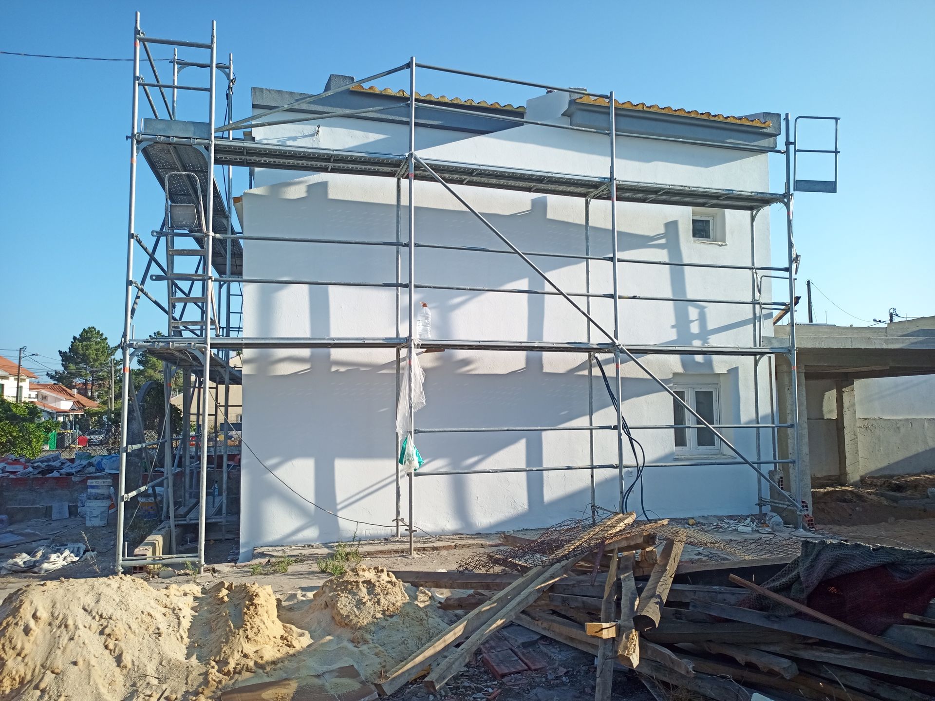 Prédio branco em construção com andaimes.
