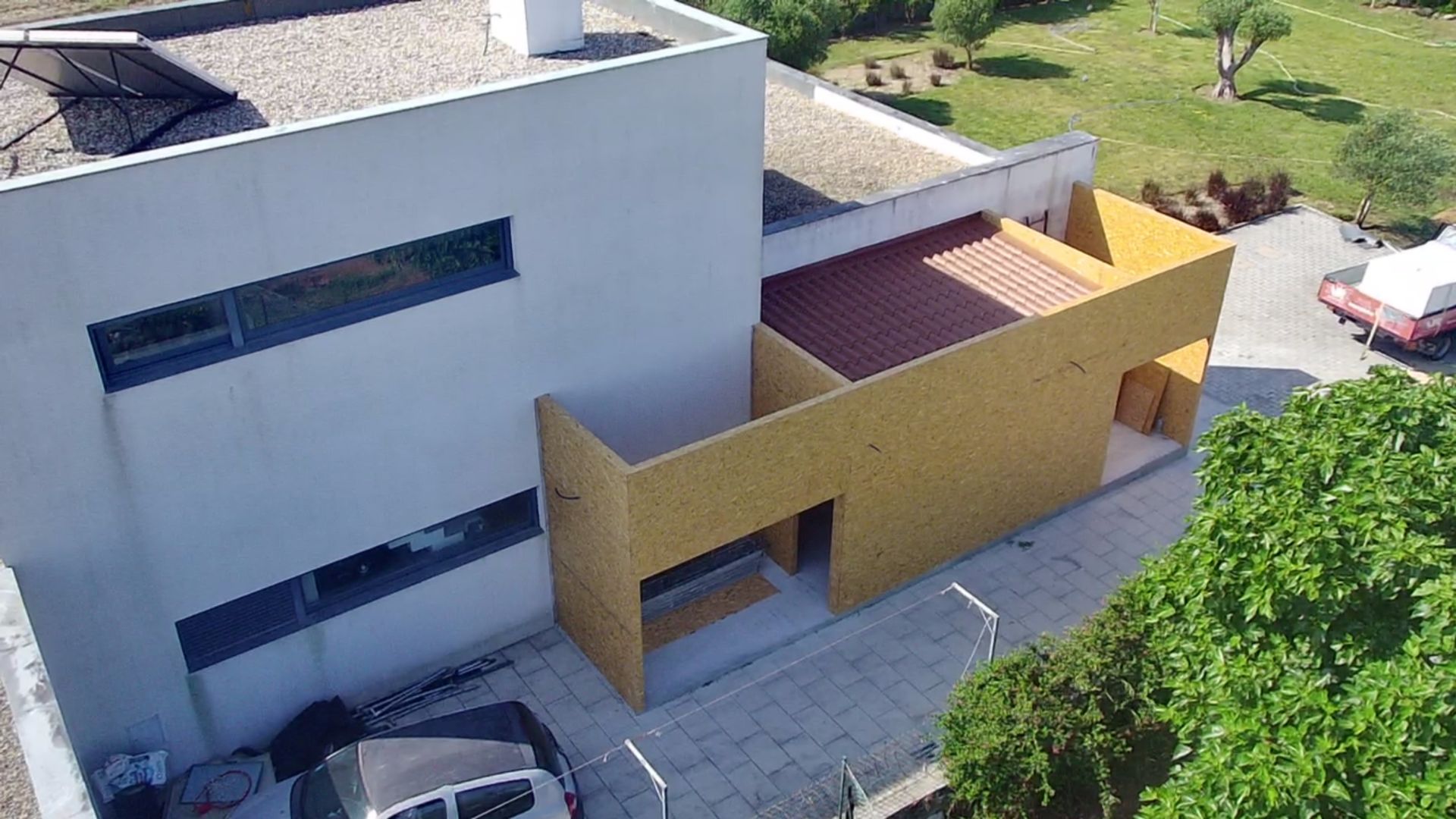 Casa moderna amarela e branca com telhado de telhas vermelhas, situada em um gramado verde e ensolarado.