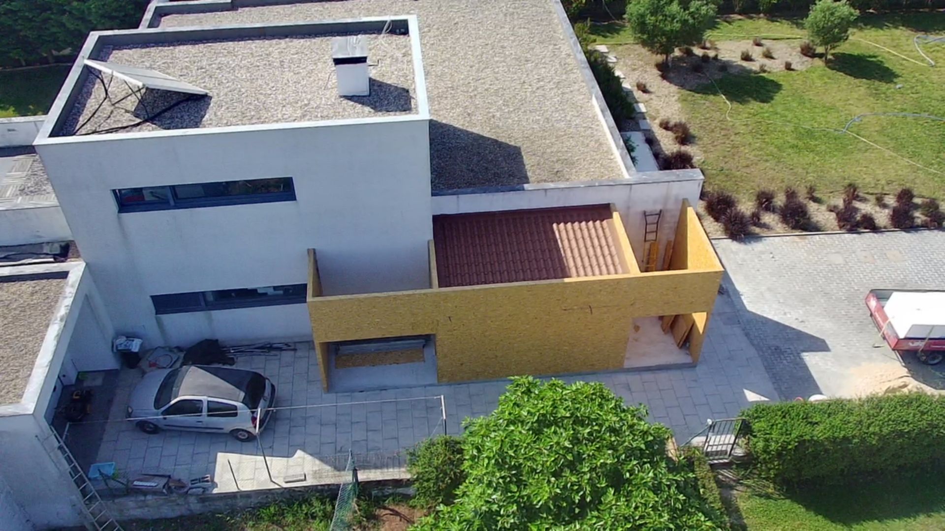 Casa moderna com seções brancas e amarelas, telhado vermelho e um carro estacionado.