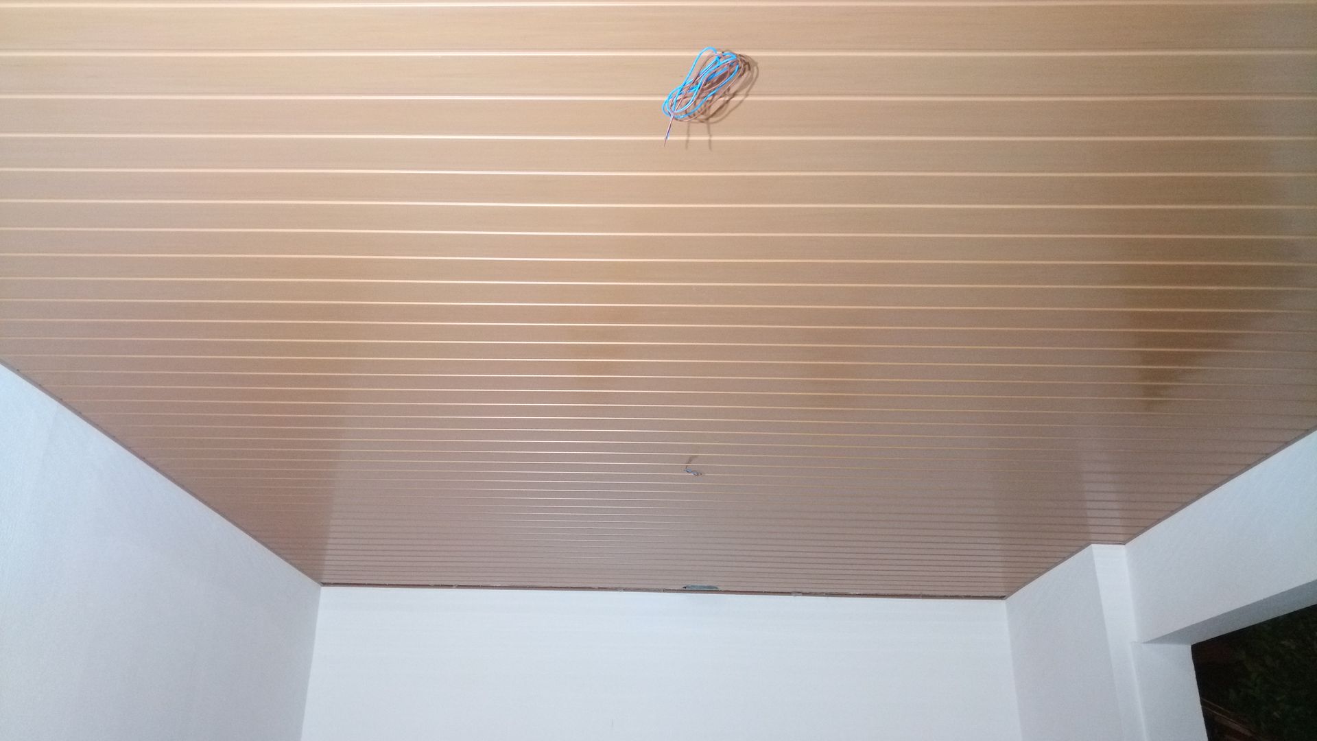 Teto com painéis bege, fiação aparente e paredes brancas.