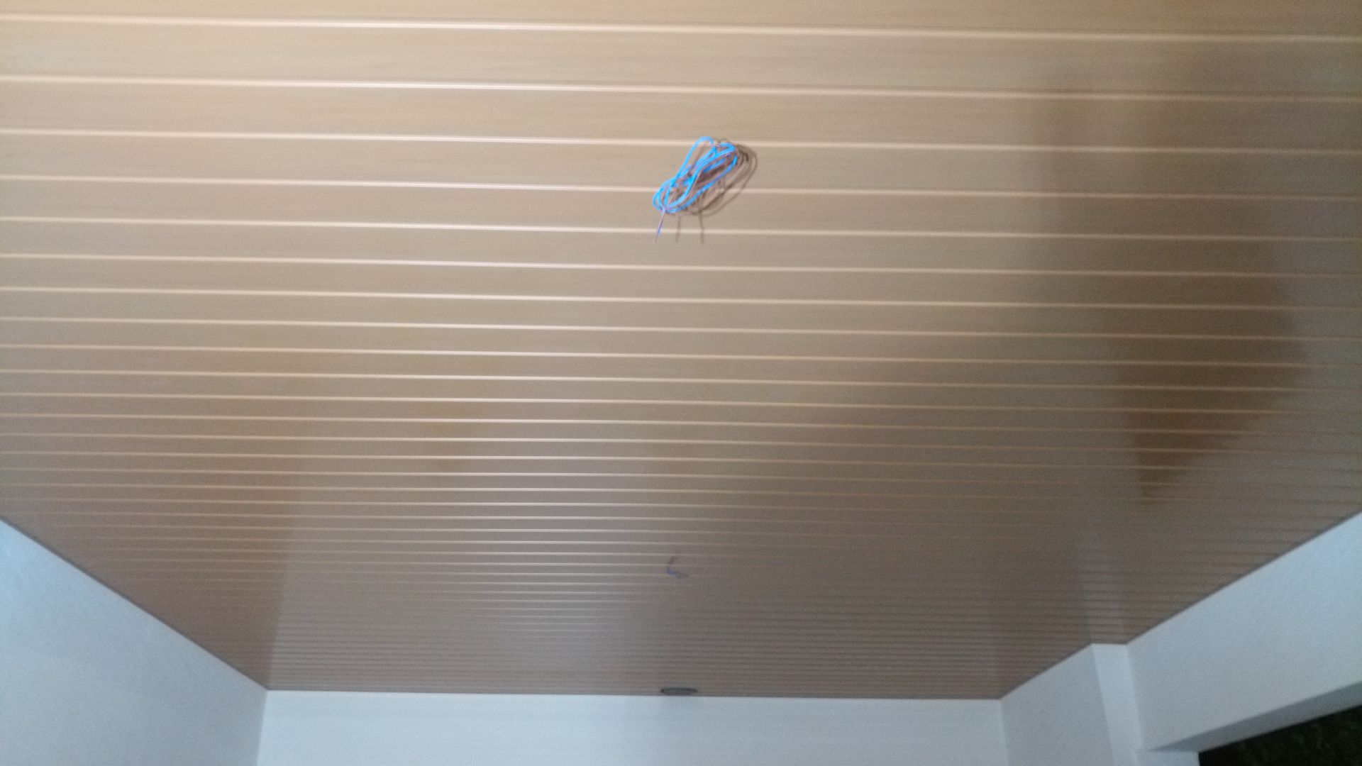 Teto bege com frisos horizontais e fiação aparente. Paredes brancas.