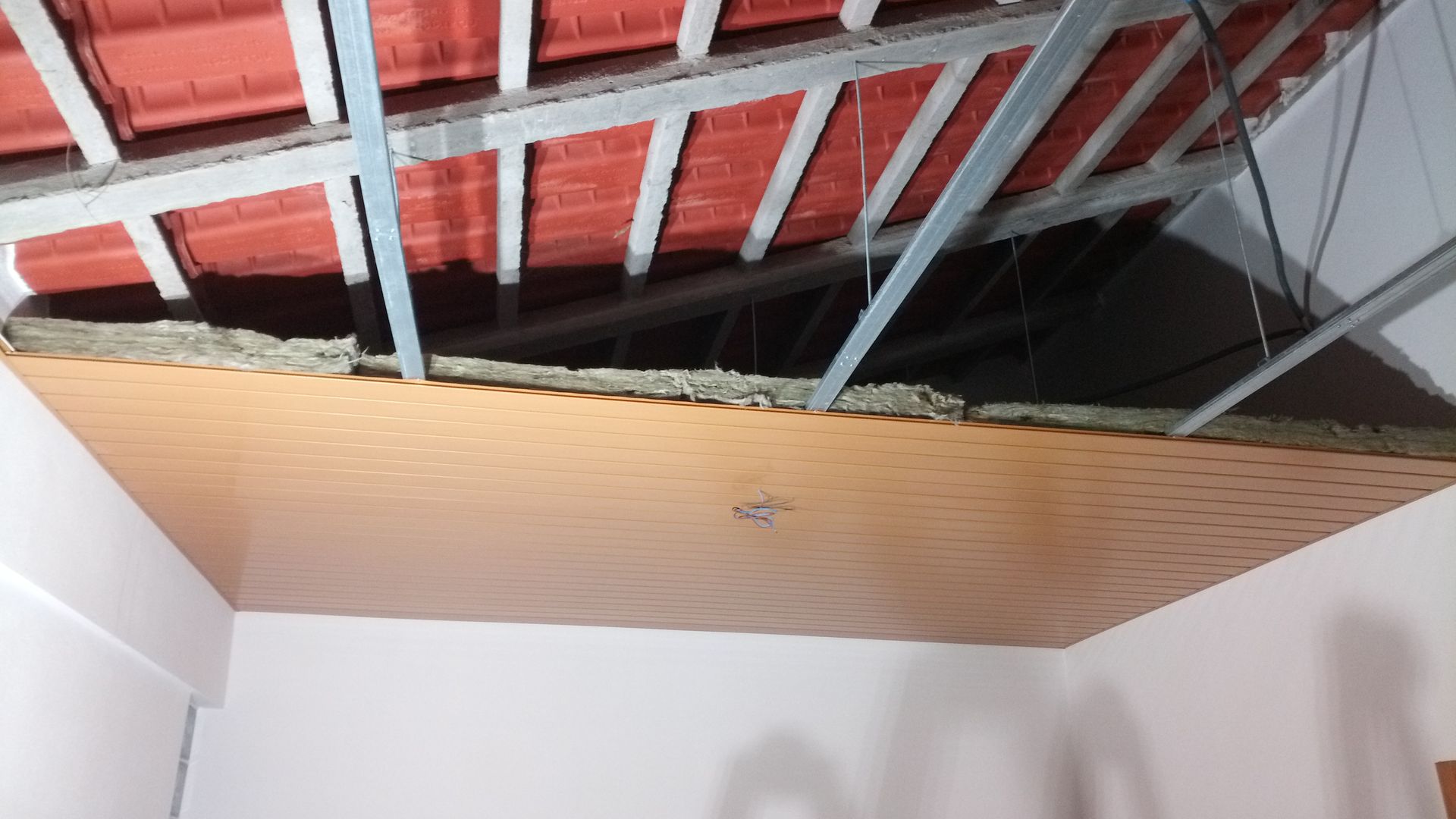 Teto danificado com cobertura exposta e painéis estampados em tons de marrom.