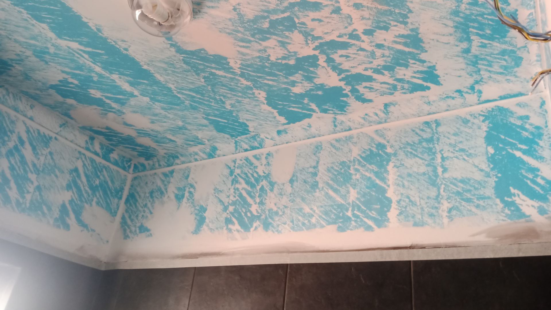 Teto com estampa azul e branca em um cômodo com parede escura.