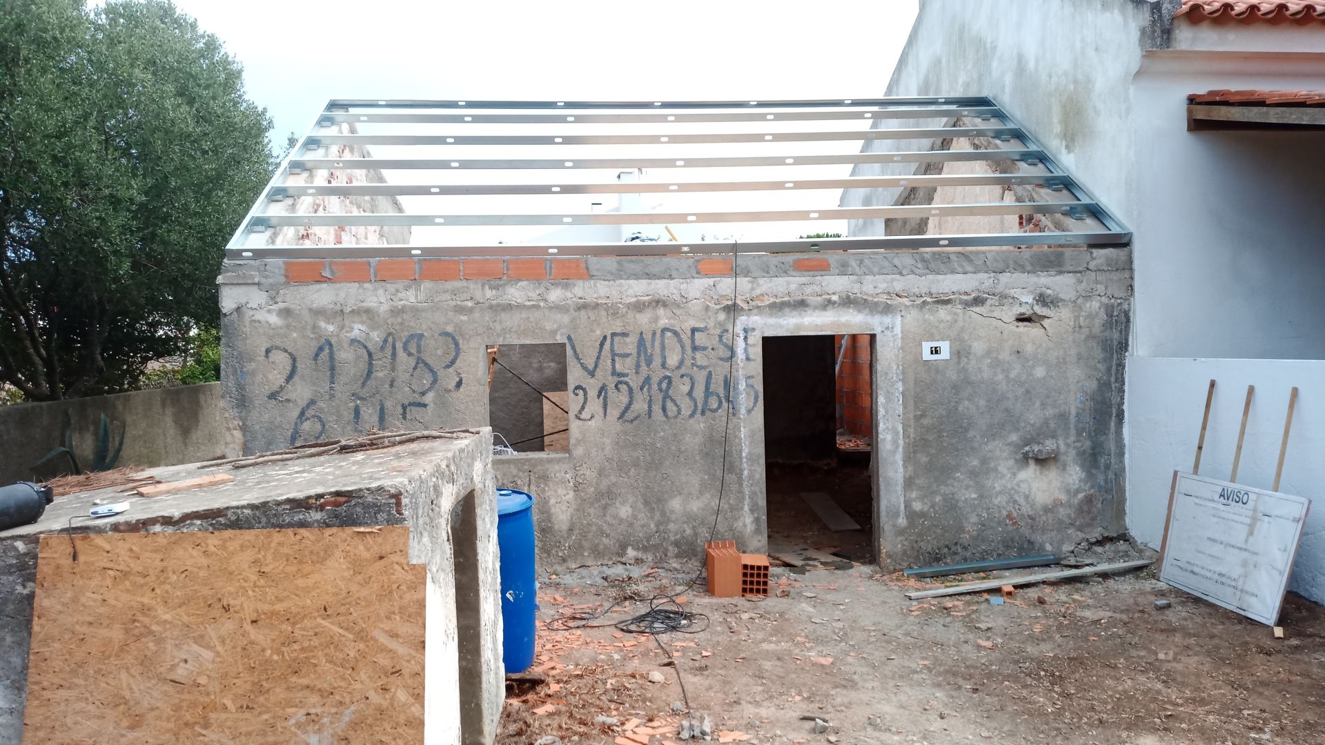 Estrutura de prédio em ruínas, sem telhado, sem porta e com a inscrição 