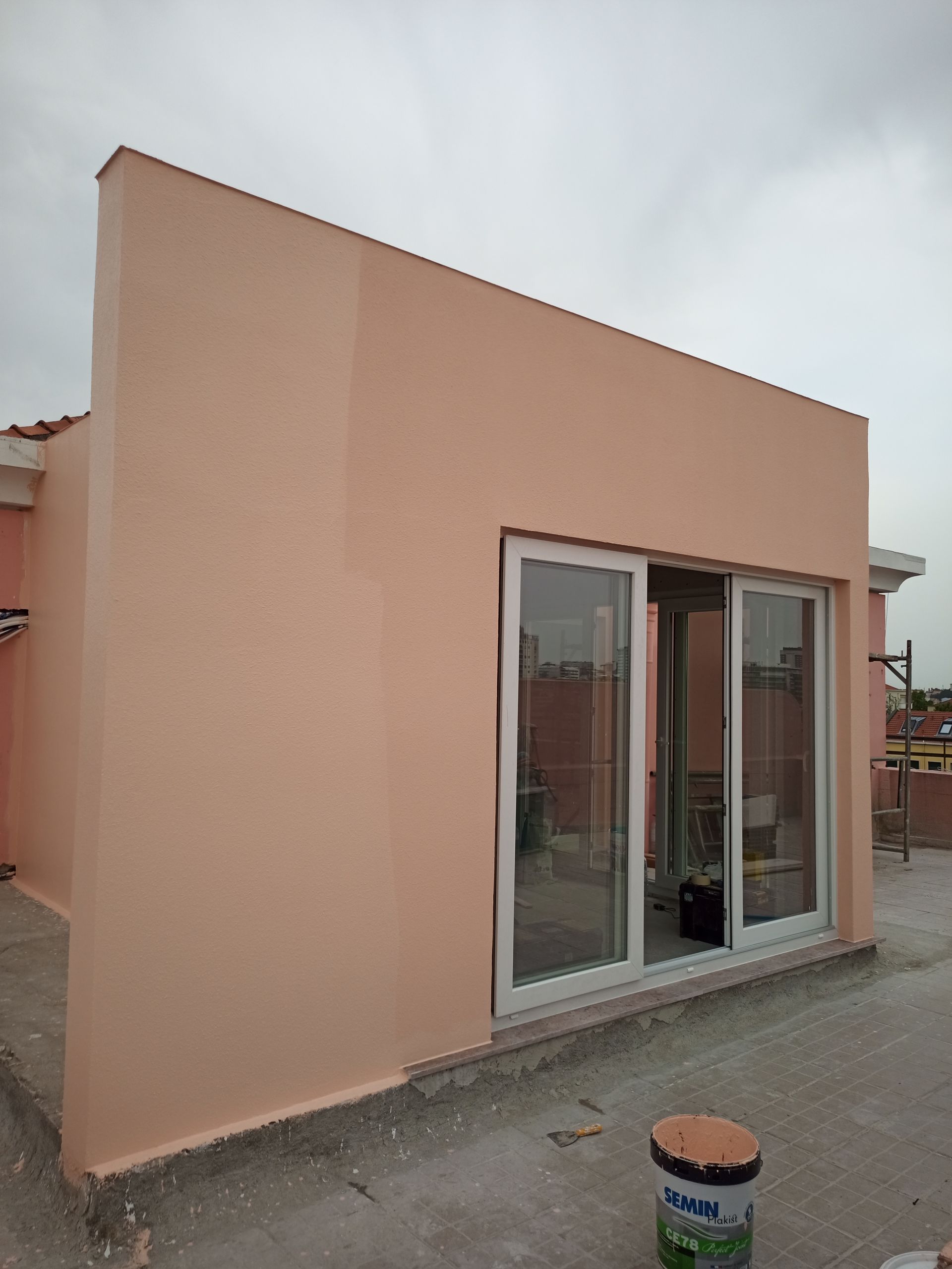 Exterior do edifício com paredes cor de pêssego e portas de vidro deslizantes contra um céu nublado.