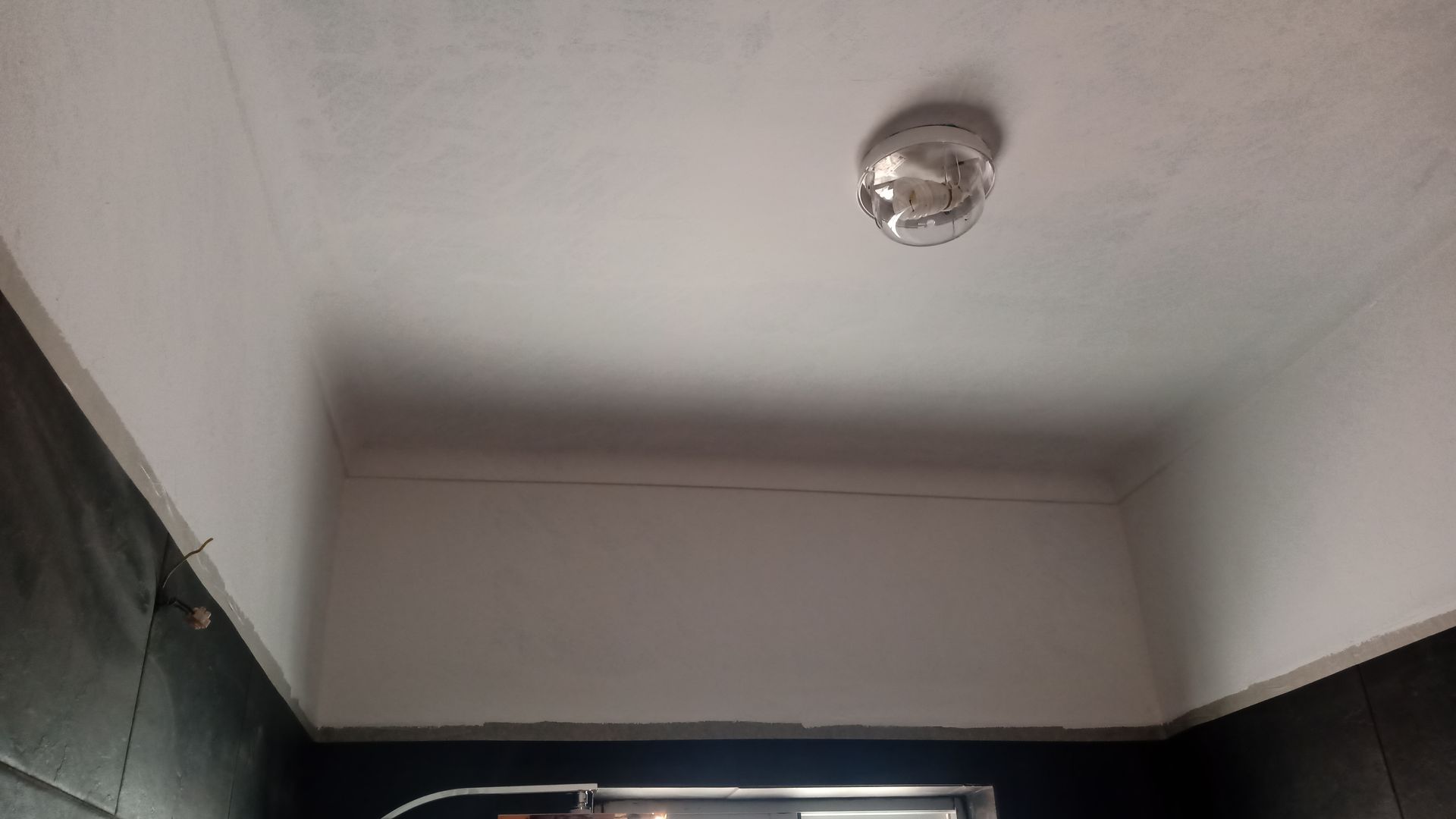 Teto com detector de fumaça, pintado de branco, e parede inferior em azul escuro.