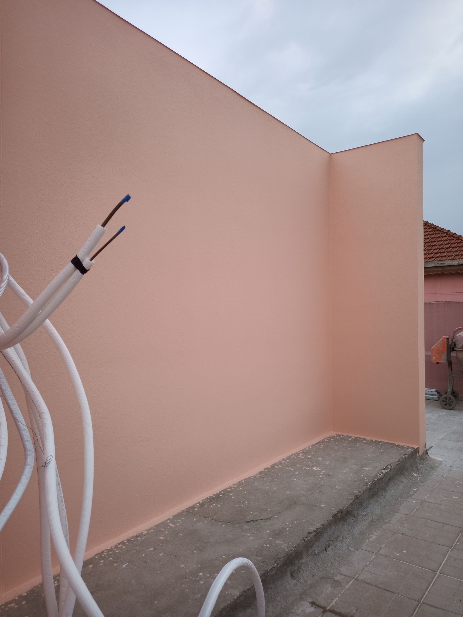 Paredes externas cor de pêssego com fios elétricos expostos contra um céu nublado.