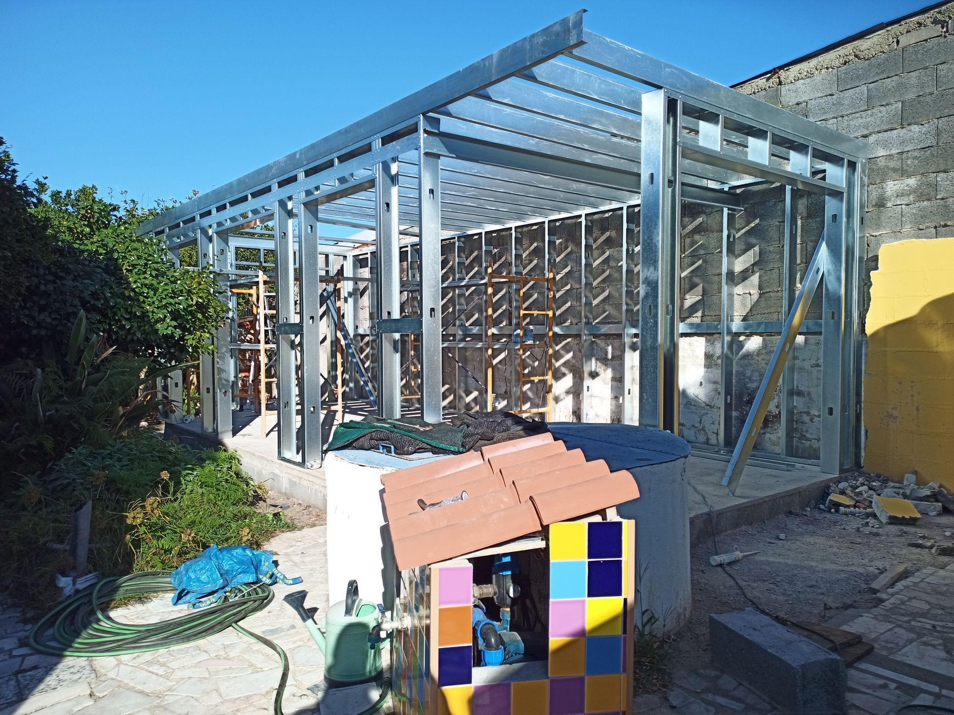 Edifício com estrutura metálica em construção, vista externa, muita luz solar.