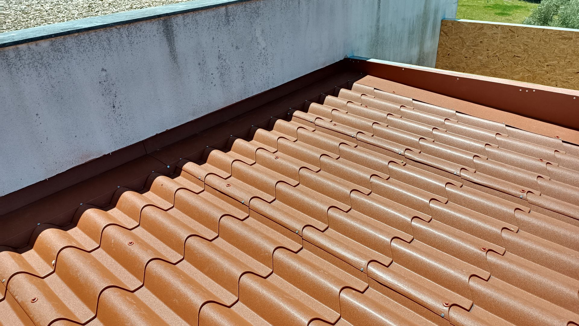 Telhado de telha marrom ao lado de uma parede de concreto e painéis de madeira.