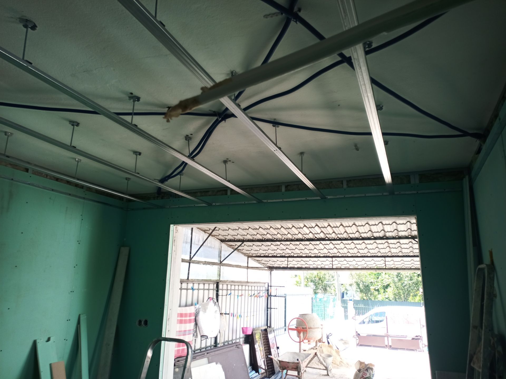 Vista interior de uma sala com estrutura de teto, vigas de sustentação visíveis e uma pessoa na porta.