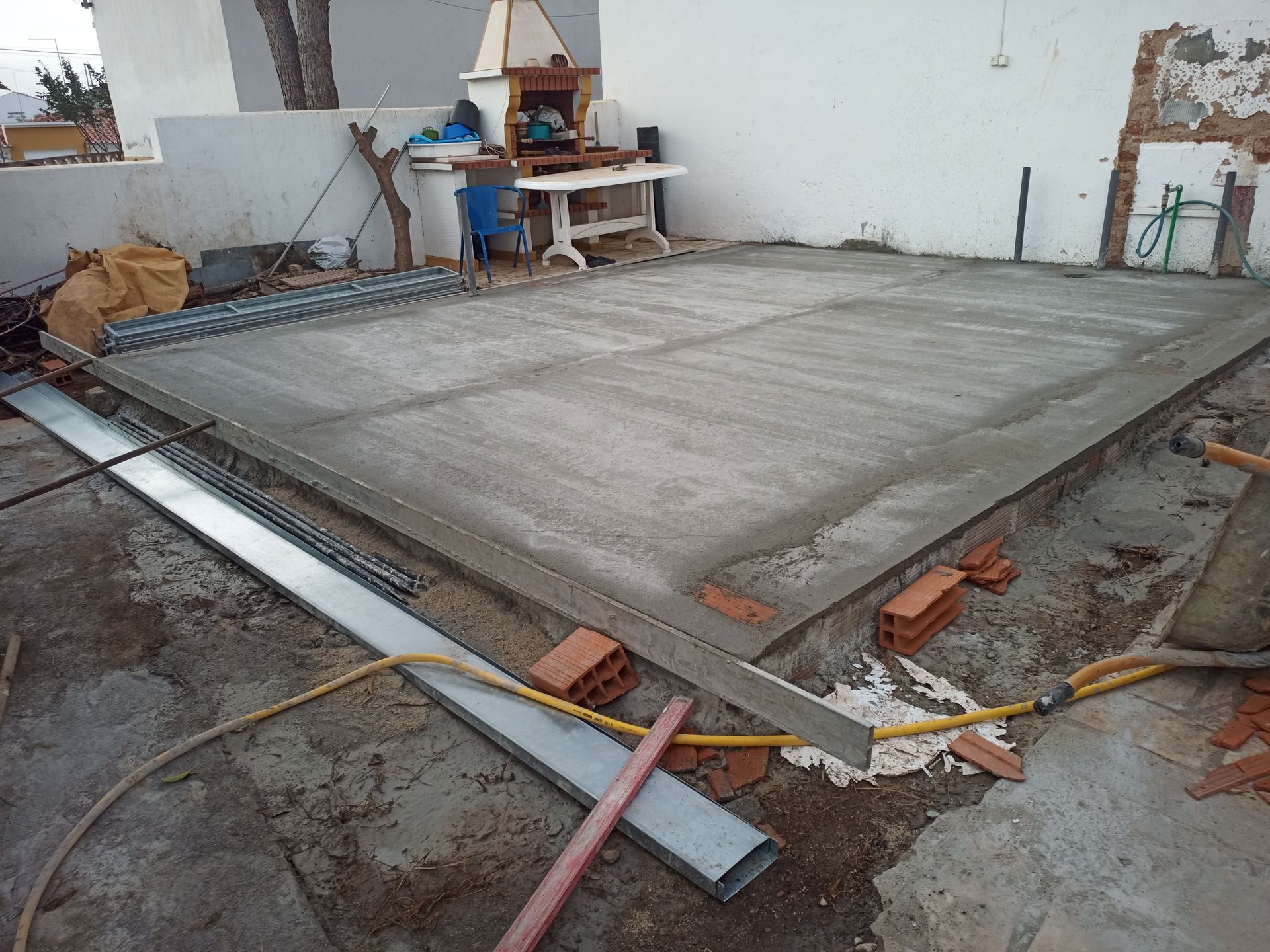 Laje de concreto recém-lançada em ambiente externo, com ferramentas e materiais de construção espalhados ao redor.