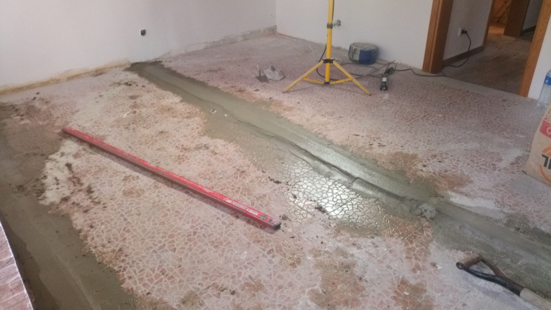 Piso de concreto sendo trabalhado com uma faixa de concreto nivelada e úmida, em ambiente interno.