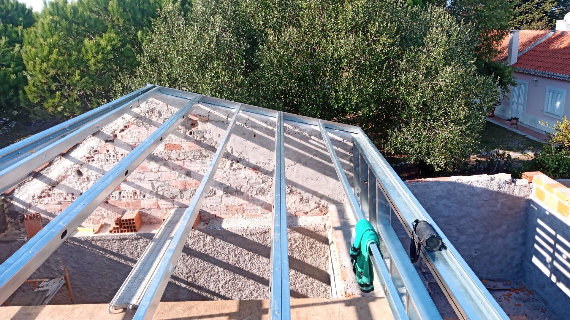 Estrutura do telhado de um edifício de tijolos com árvores ao fundo.