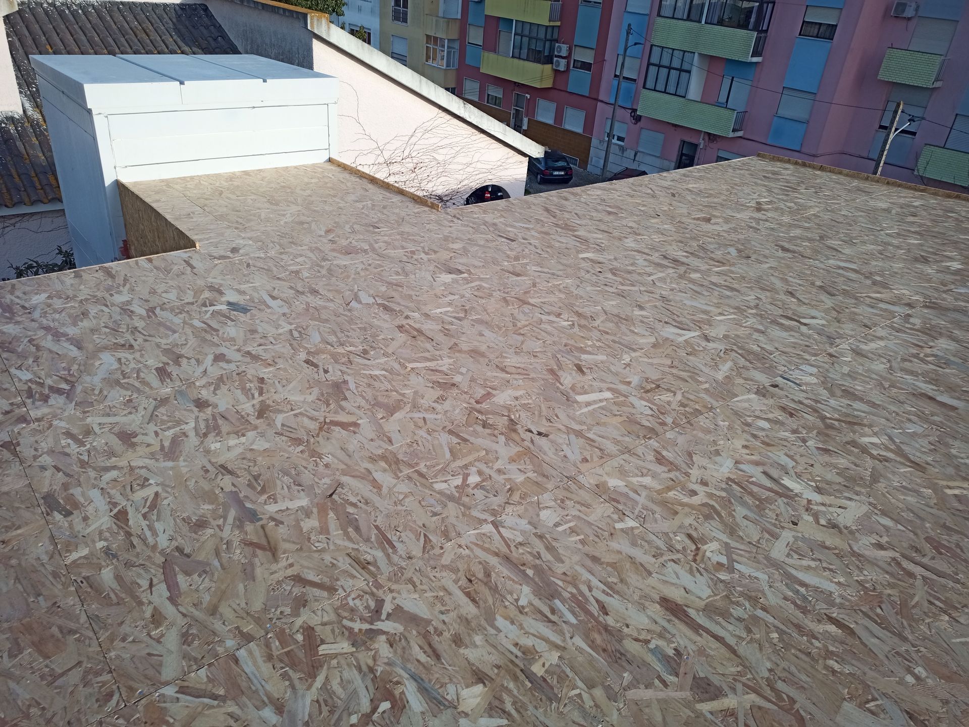 Telhado de OSB (Oriented Strand Board) em construção, com o prédio ao fundo.