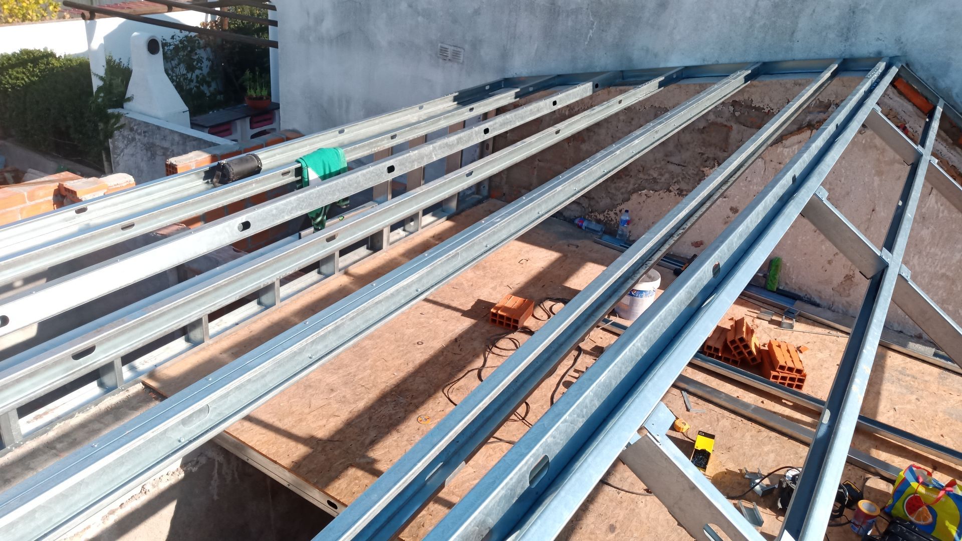 Estrutura de aço para telhado sobre uma fachada de tijolos, em processo de construção.