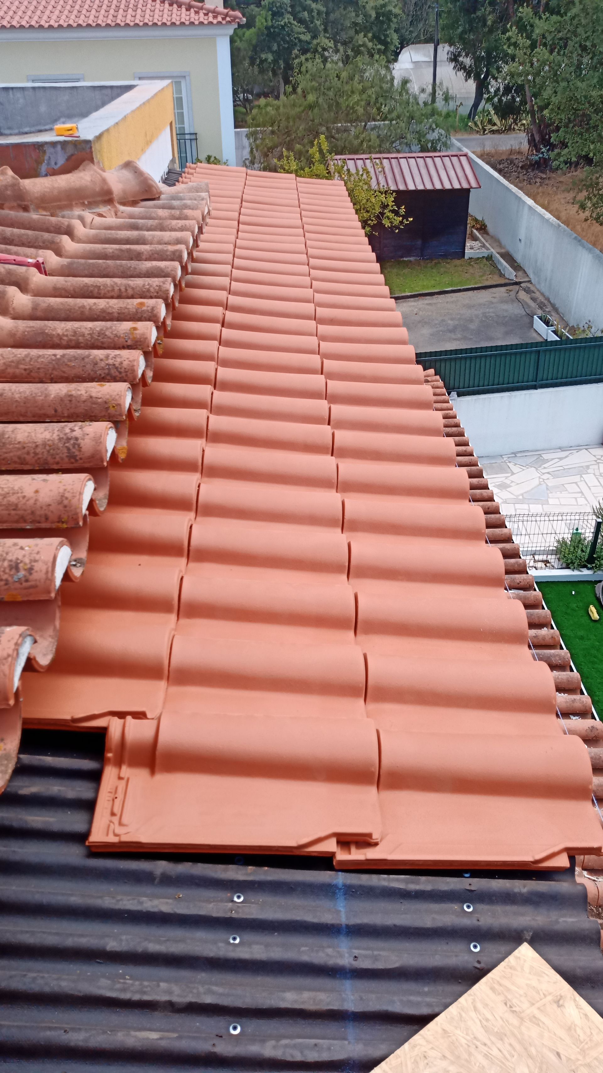 Telhas de terracota sendo instaladas no telhado de uma casa.