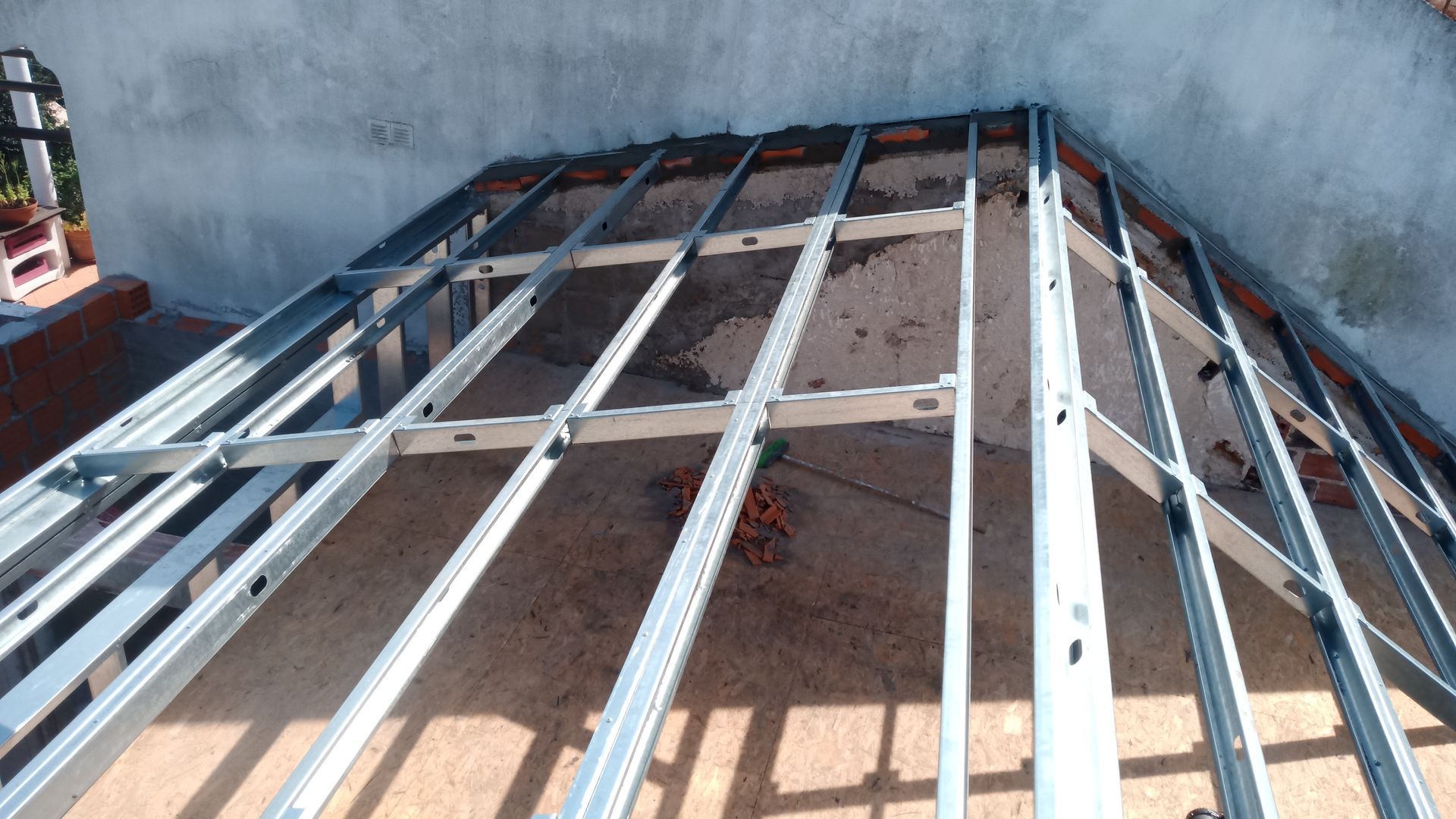 Estrutura metálica sobre uma superfície de tijolo e concreto, possivelmente para uma cobertura ou forro.