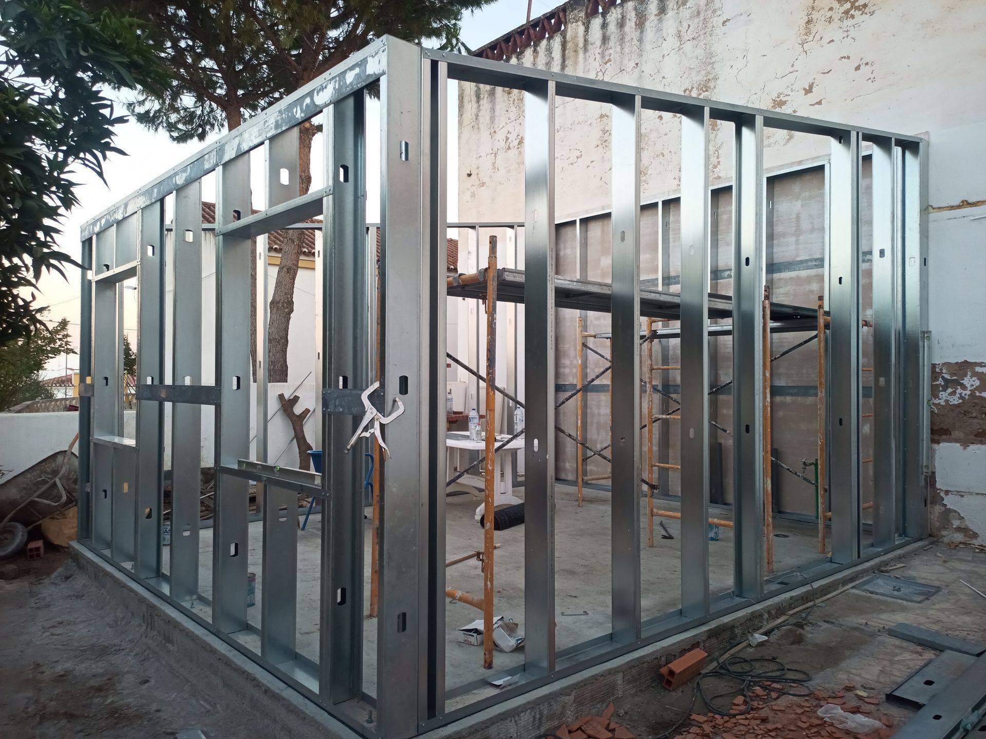 Estrutura metálica de um edifício em construção, mostrando paredes, janelas e aberturas de portas, na parte externa.