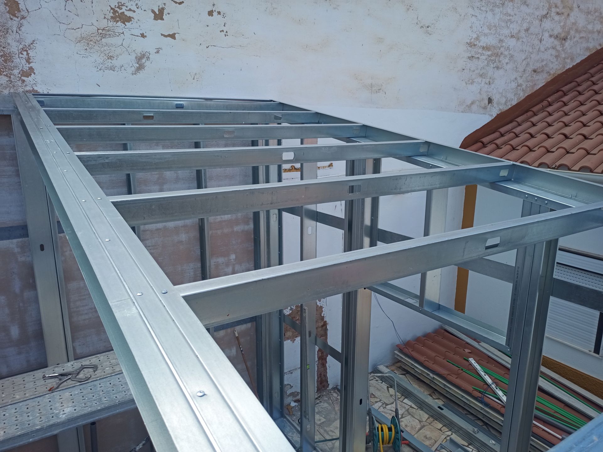 Estrutura metálica de um novo edifício, possivelmente um telhado ou uma extensão, sendo construída ao ar livre.