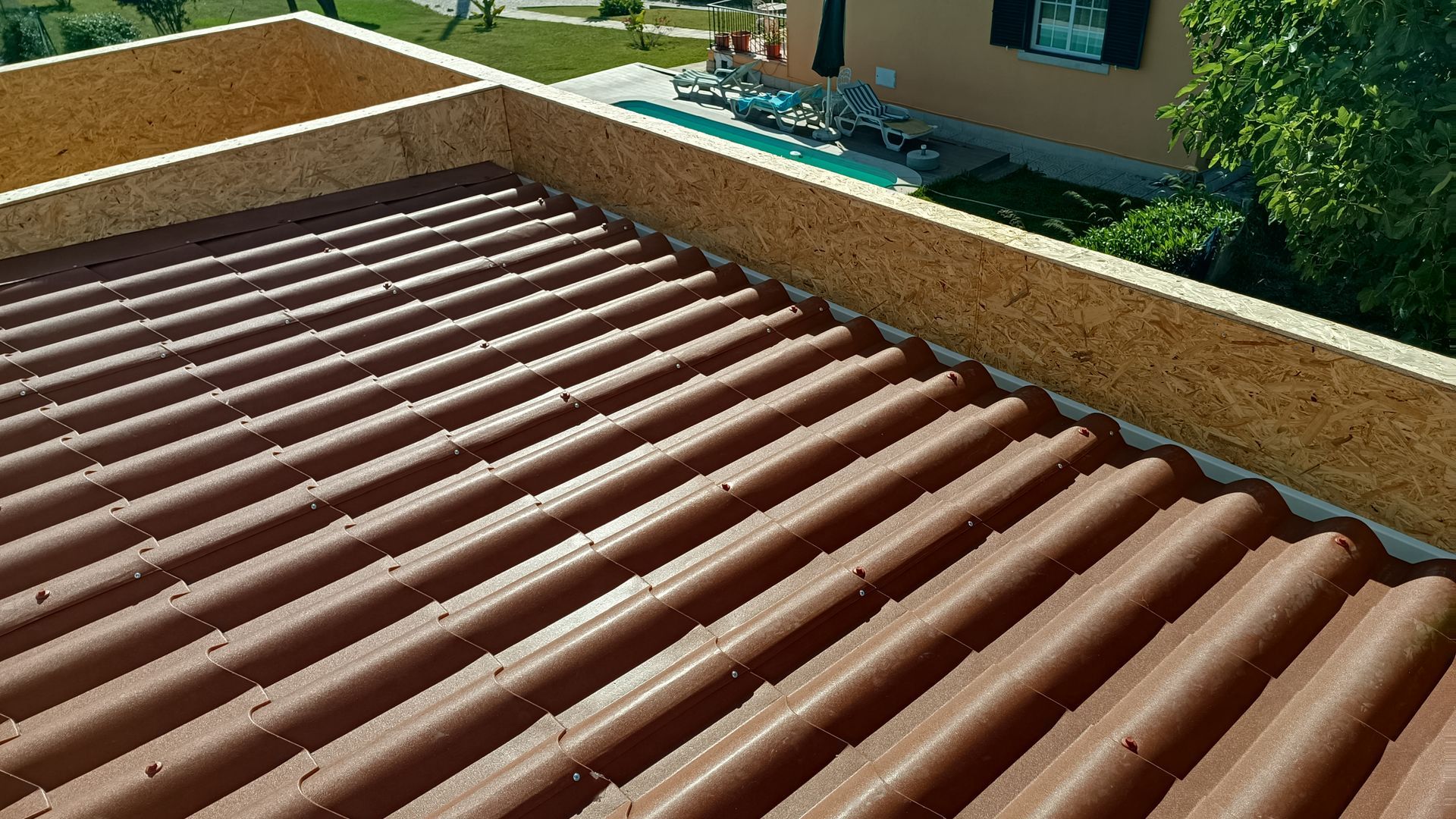 Telhado ondulado marrom com acabamento em madeira, vista aérea do telhado de um edifício.