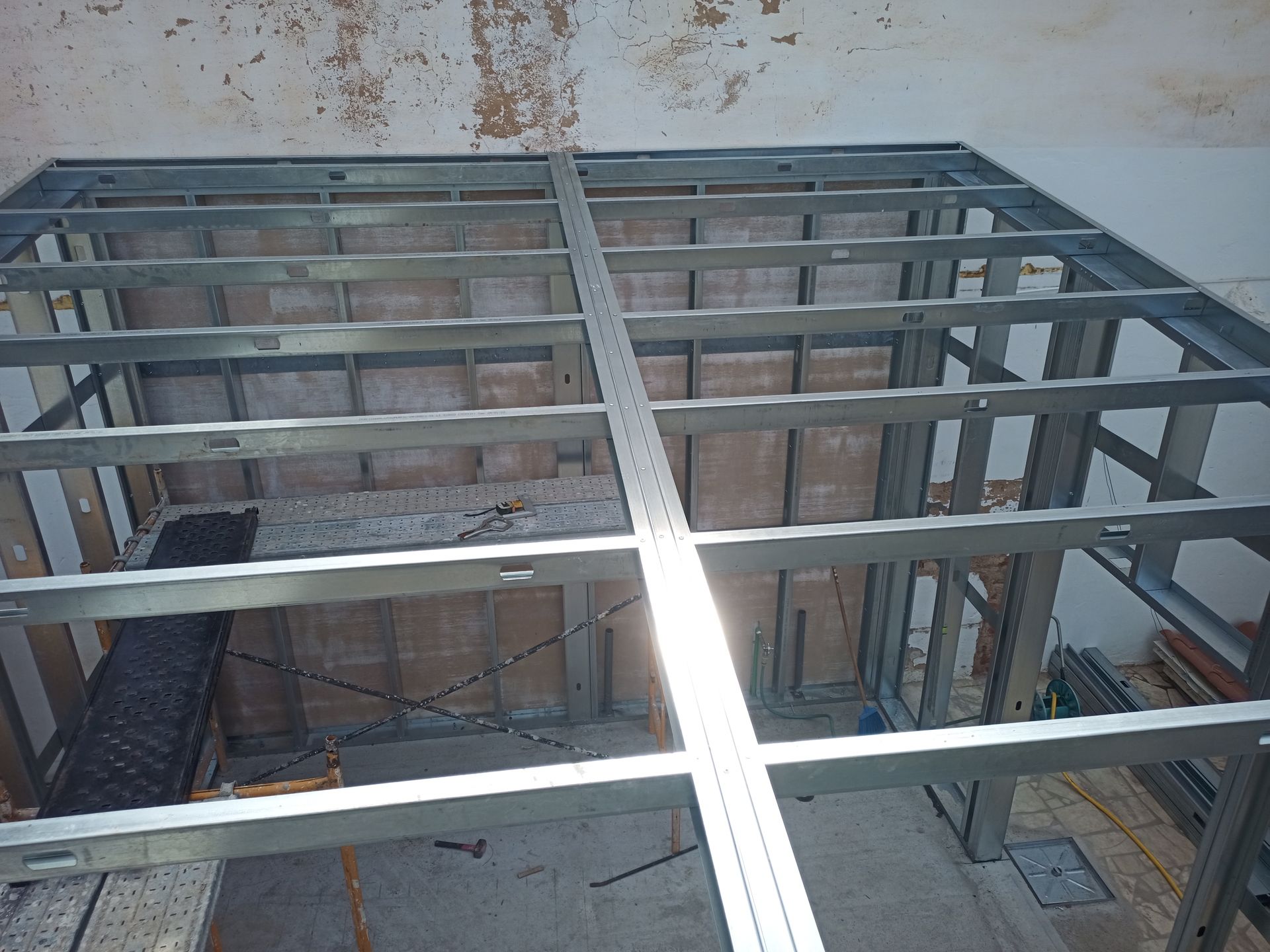 Estrutura de aço para teto ou piso em um contexto de construção. Padrão quadriculado, vigas de sustentação visíveis.