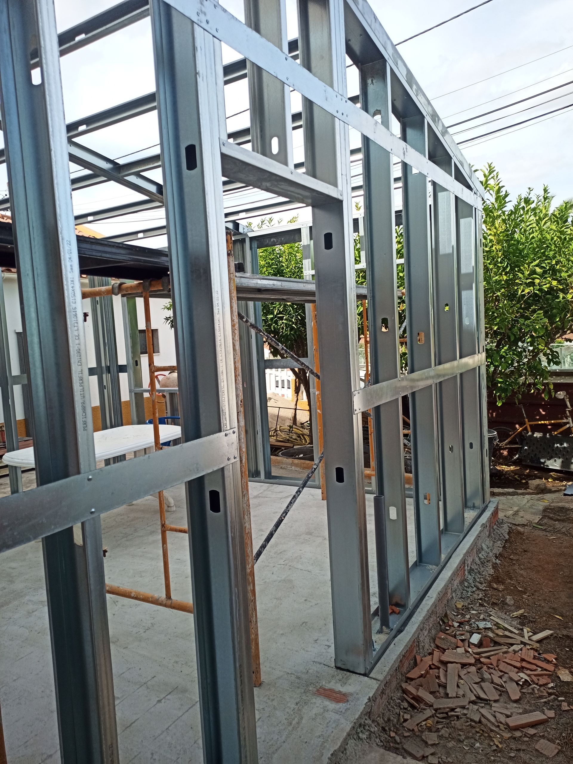 Estrutura metálica de um edifício em construção, mostrando os montantes das paredes e os batentes das portas. Ambiente externo.