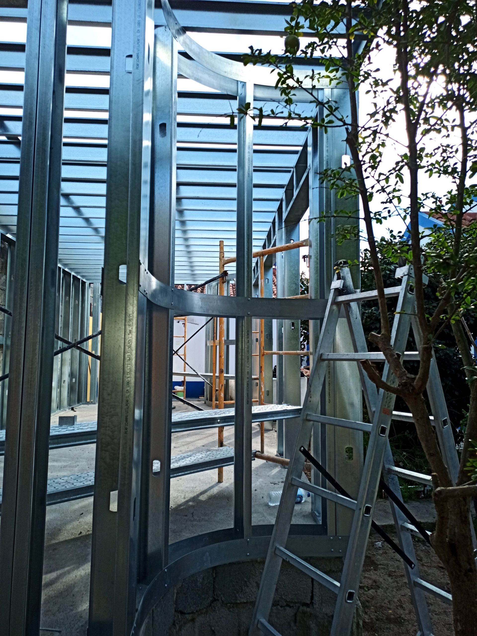 Estrutura metálica de um edifício, mostrando paredes, estrutura do teto e uma escada.