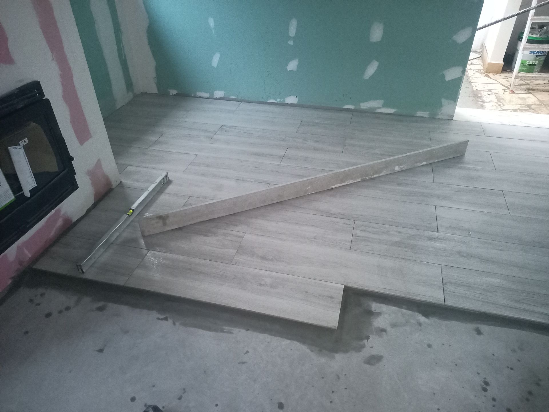 Quarto com piso inacabado, nivelado e com azulejos. Paredes de gesso e lareira visíveis.