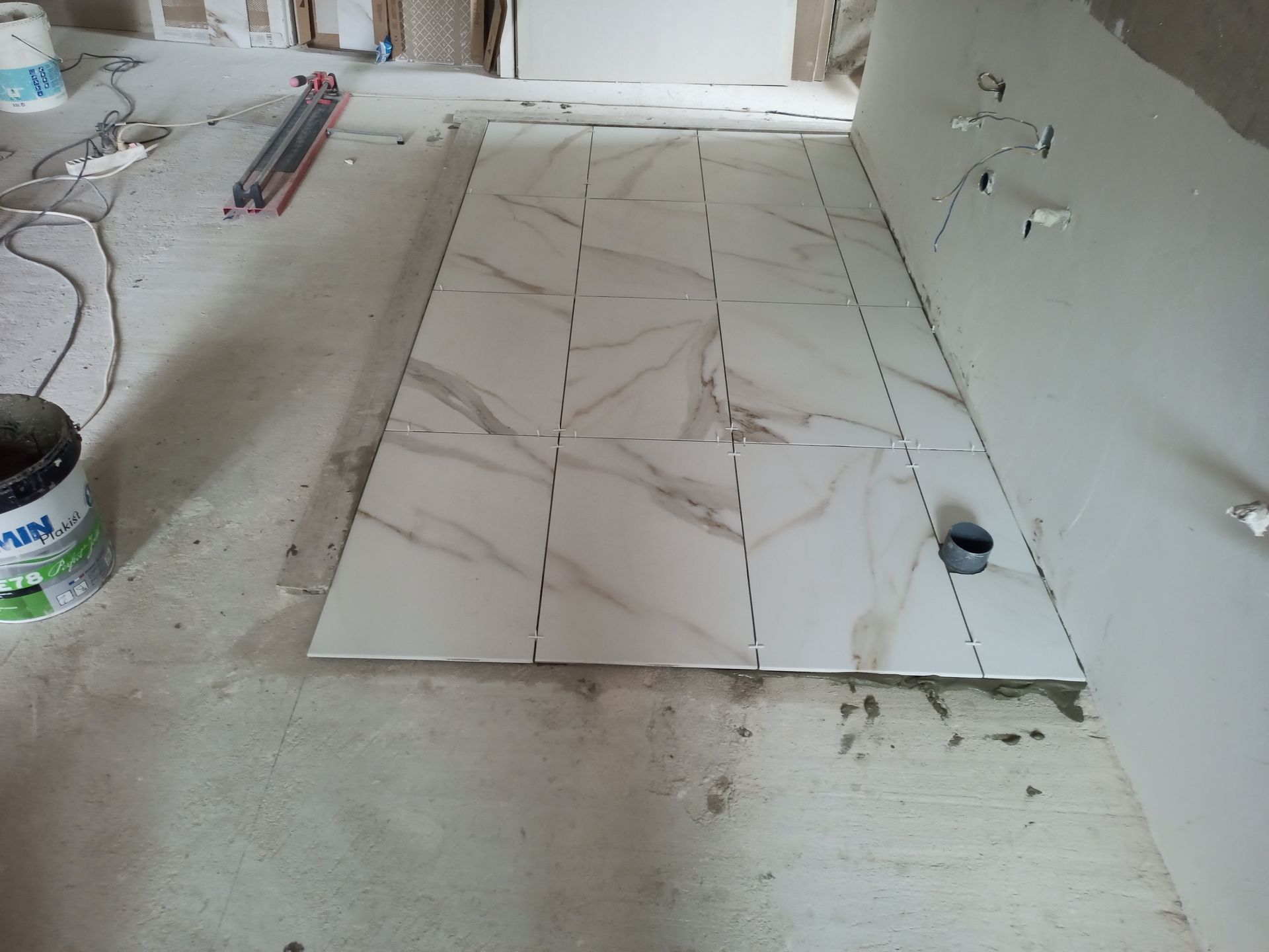 Pisos cerâmicos sendo assentados sobre concreto, interior, construção inacabada.