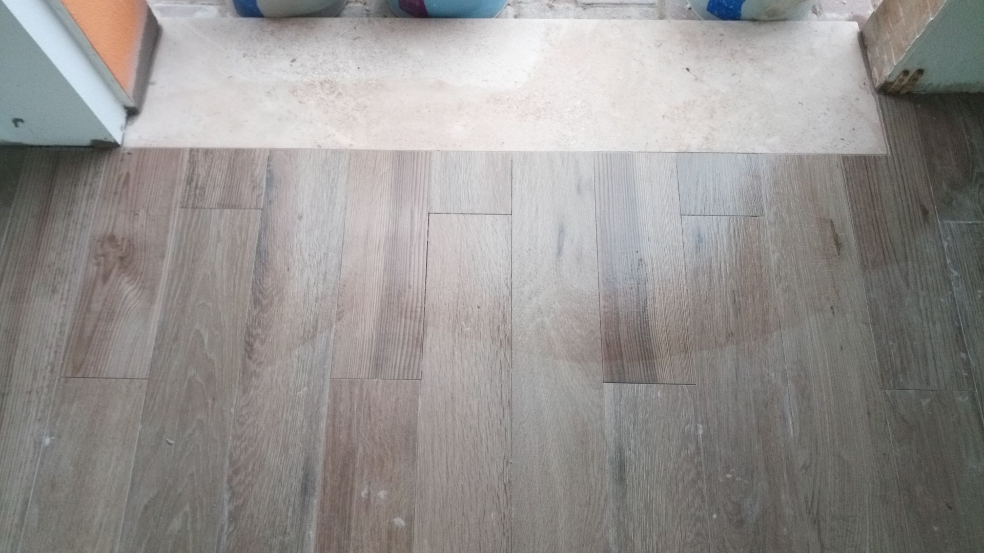 Transição de piso de madeira, com uma faixa de madeira mais clara entre as tábuas mais escuras na entrada.