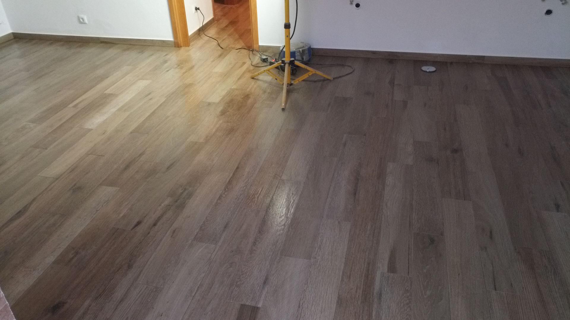 Piso de madeira em um cômodo com um suporte de luz ao fundo.