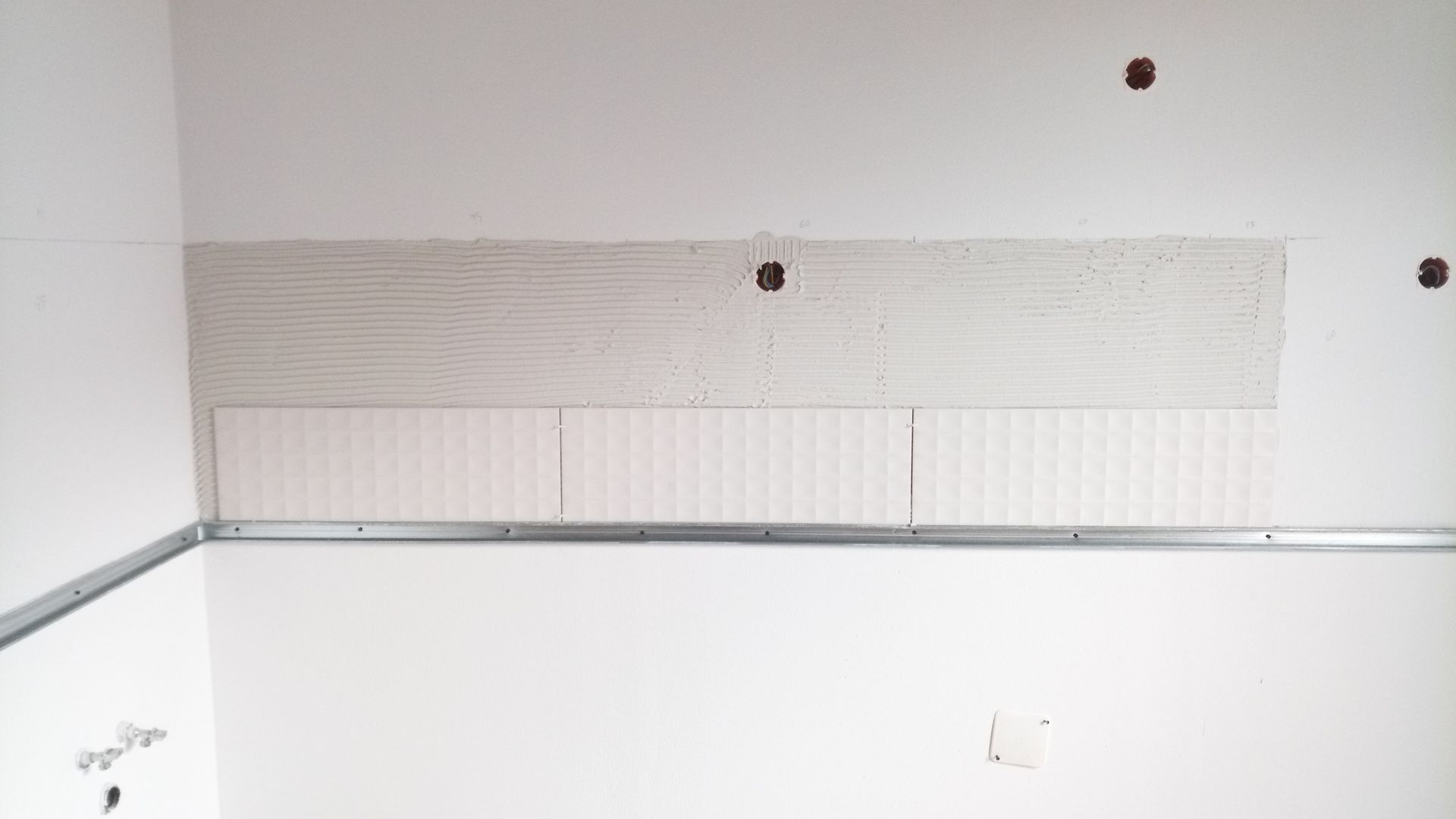 Seção da parede em construção com madeira e drywall, estrutura metálica e aberturas para instalações elétricas.