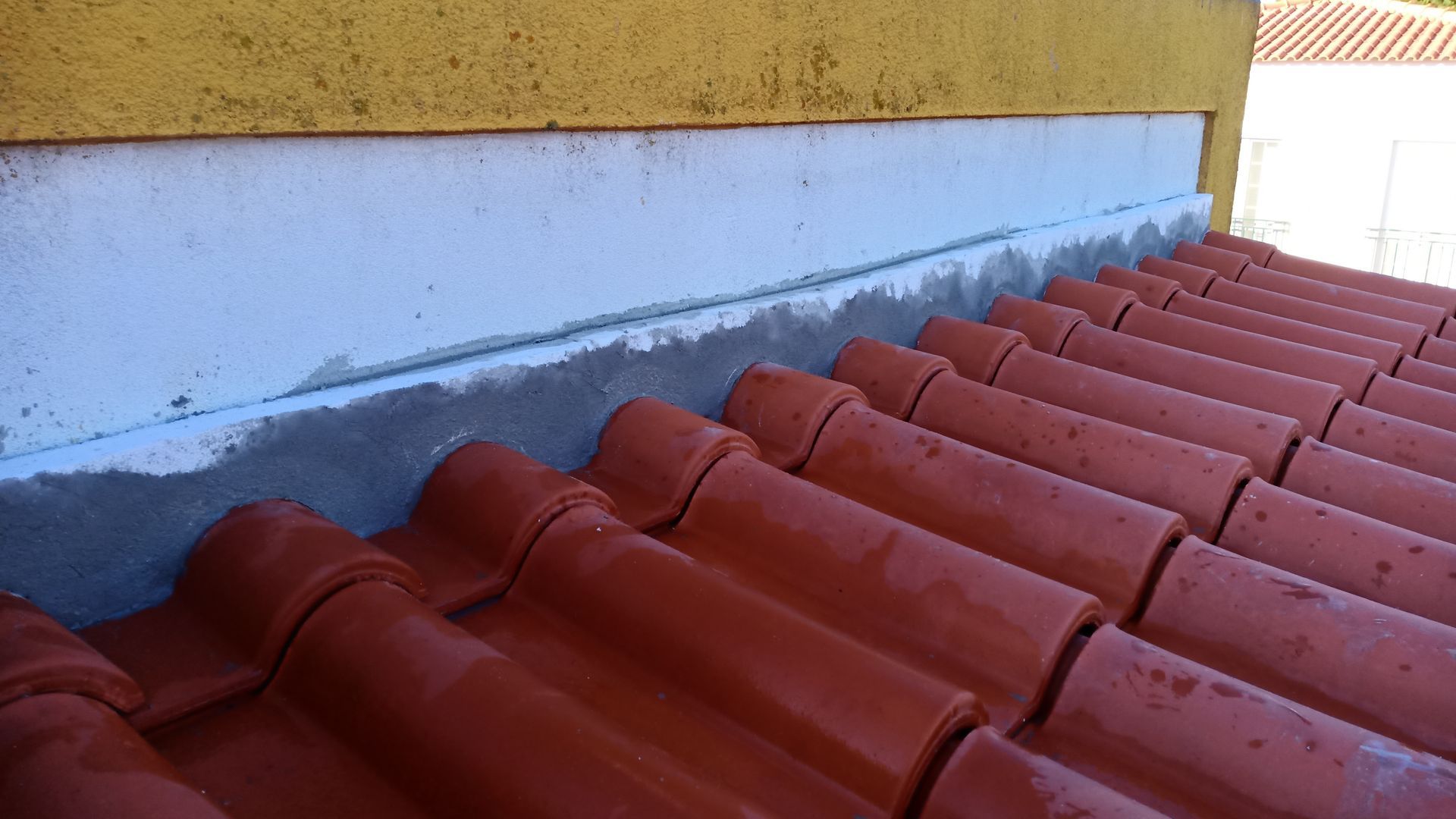 Telhas vermelhas encontram uma parede azul-clara, selada com concreto cinza. Acima, há uma parede amarela.