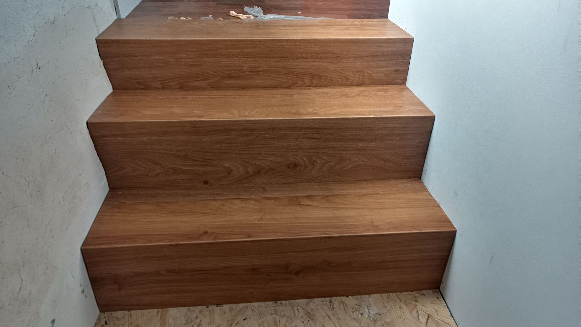 Degraus de madeira que levam para cima entre paredes brancas.