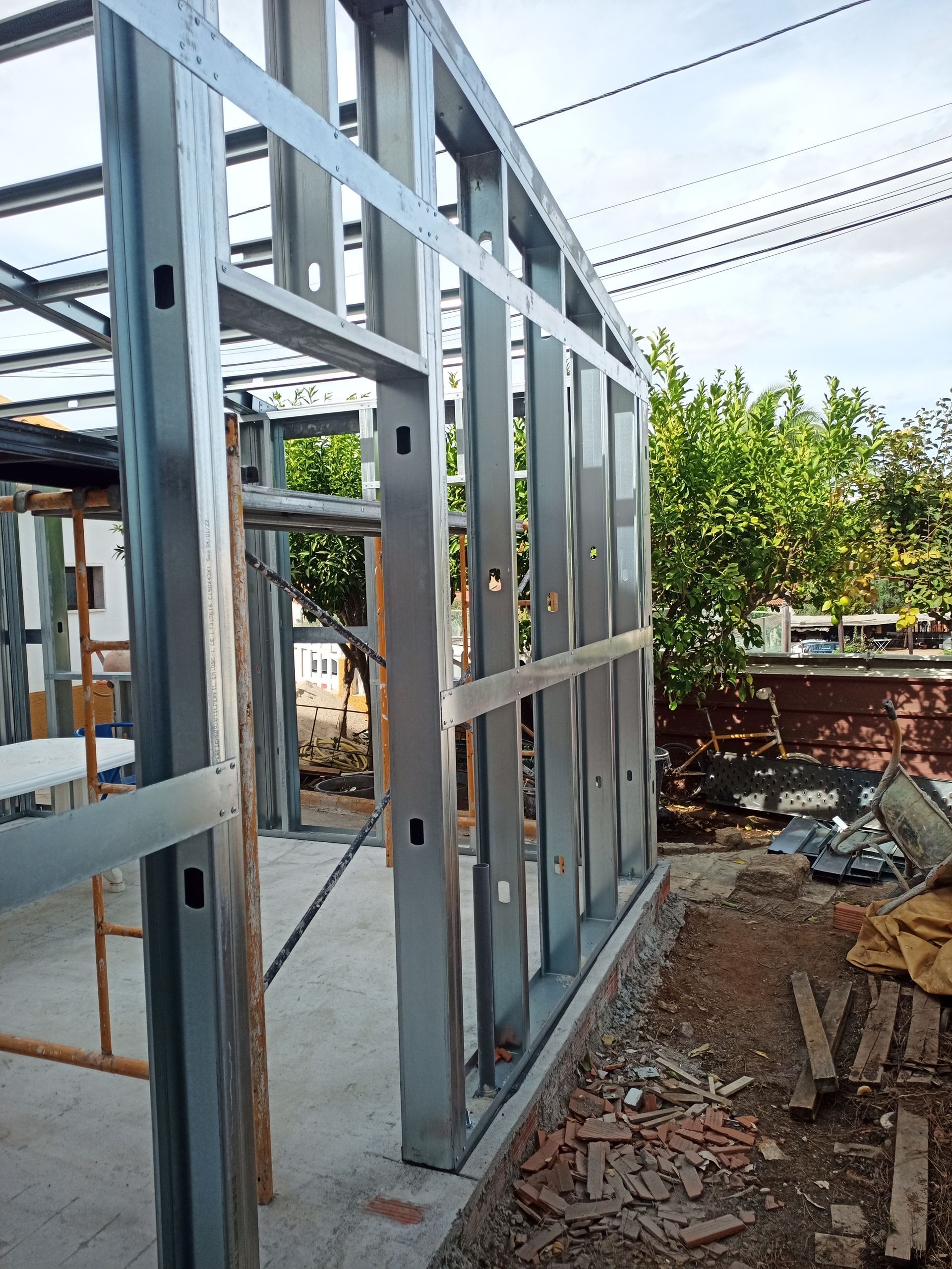 Estrutura metálica de um edifício em construção, vista exterior. São visíveis os montantes metálicos verticais, os suportes horizontais e a abertura de uma porta.