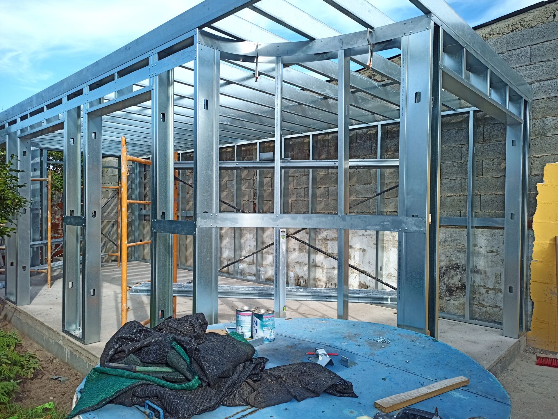 Estrutura metálica de um edifício em construção, com paredes e teto visíveis.