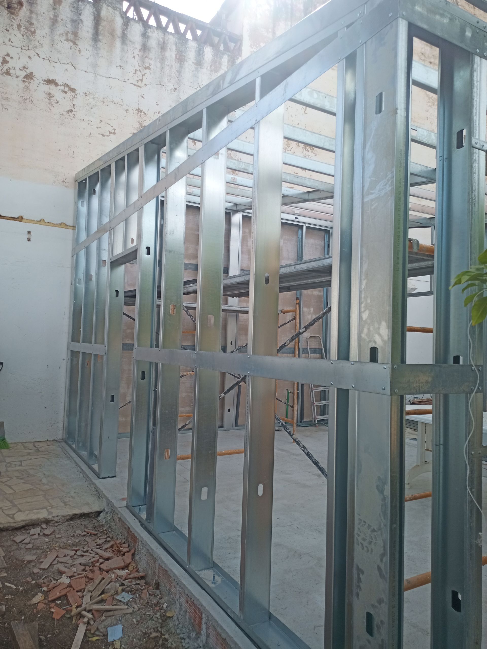 Estrutura metálica para parede interna de um edifício, inacabada e exposta. Vigas de aço cinza em um canteiro de obras.