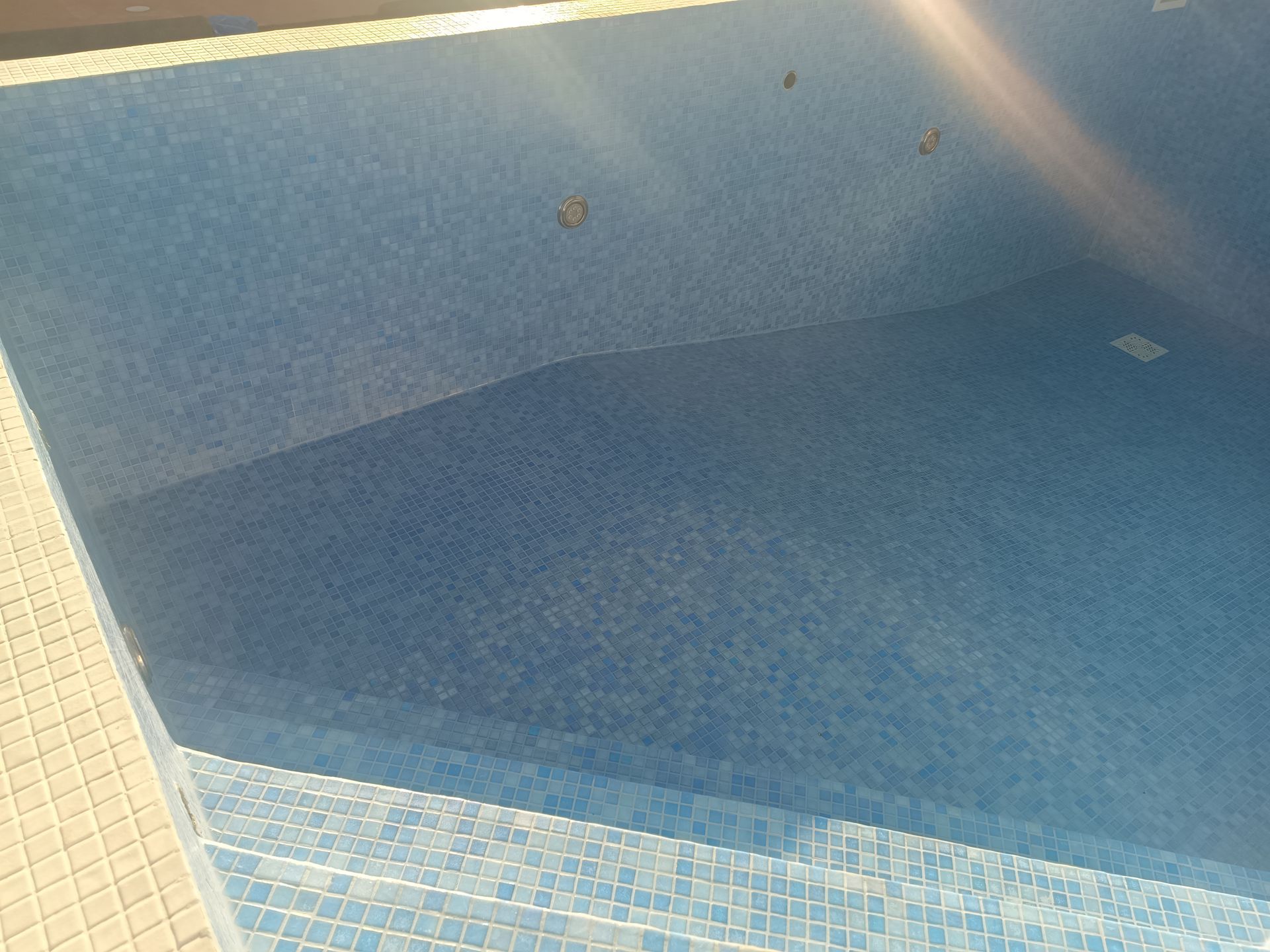 Piscina vazia revestida com azulejos azuis.