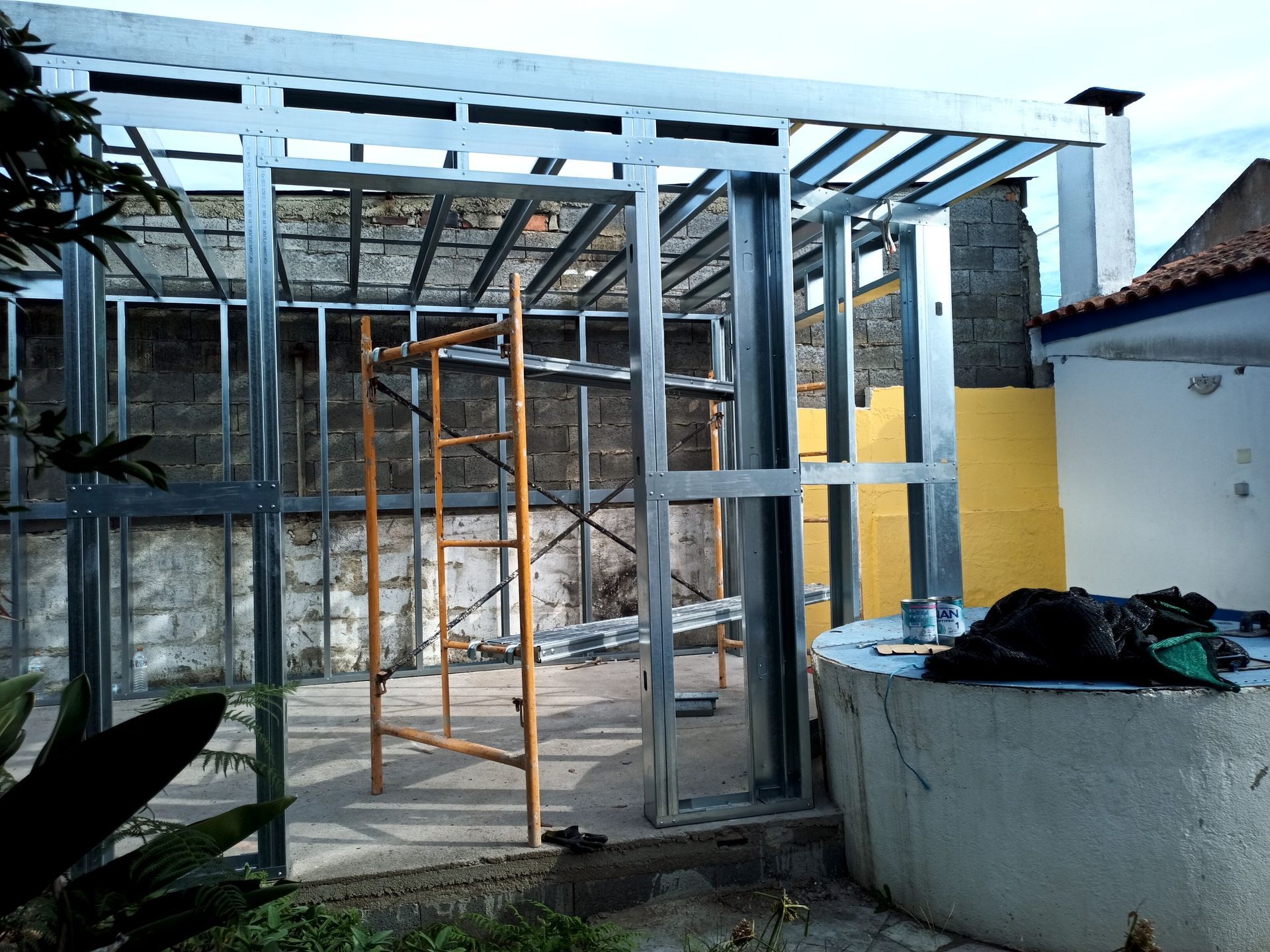 Estrutura metálica de um edifício em construção, vista exterior com uma escada no interior.