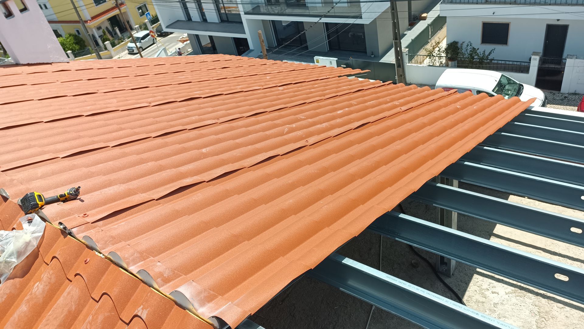 Telhado ondulado marrom sendo instalado em uma estrutura metálica, com iluminação natural externa.