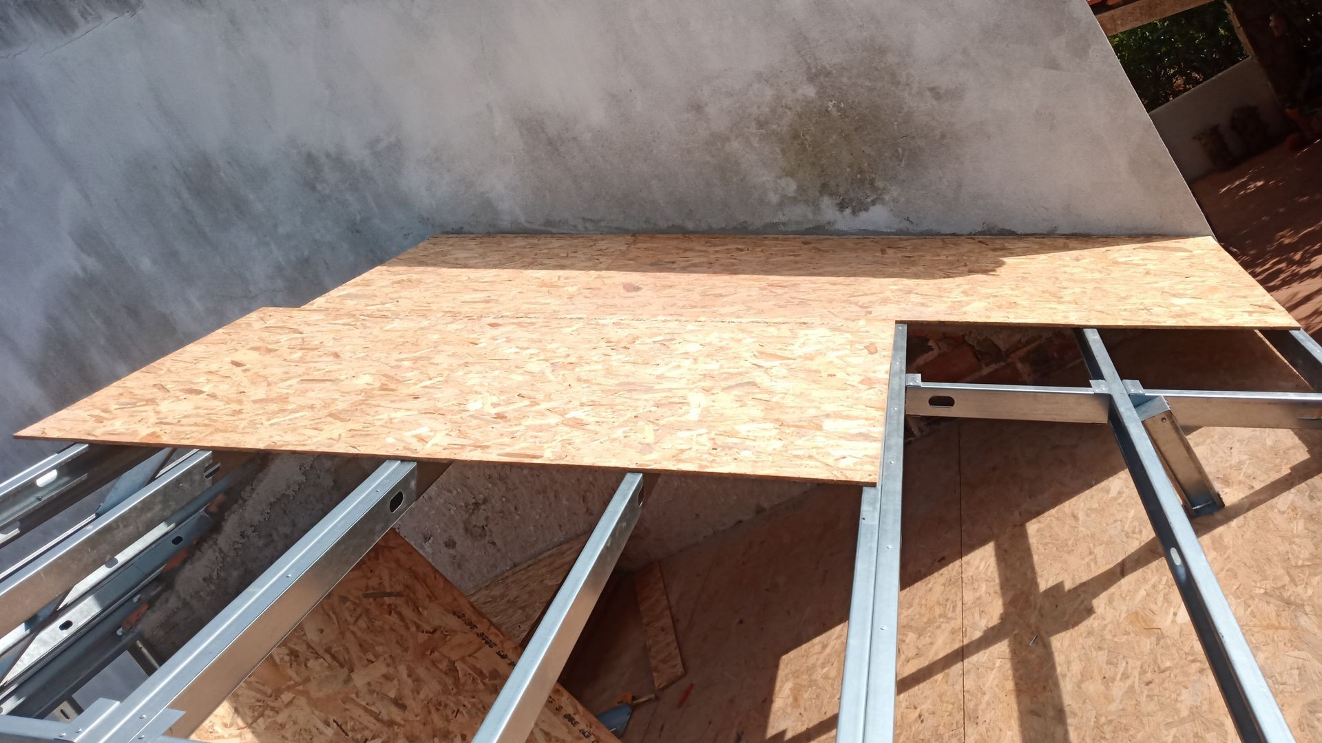 Chapa de madeira sobre estrutura metálica, cobrindo parcialmente um espaço retangular.