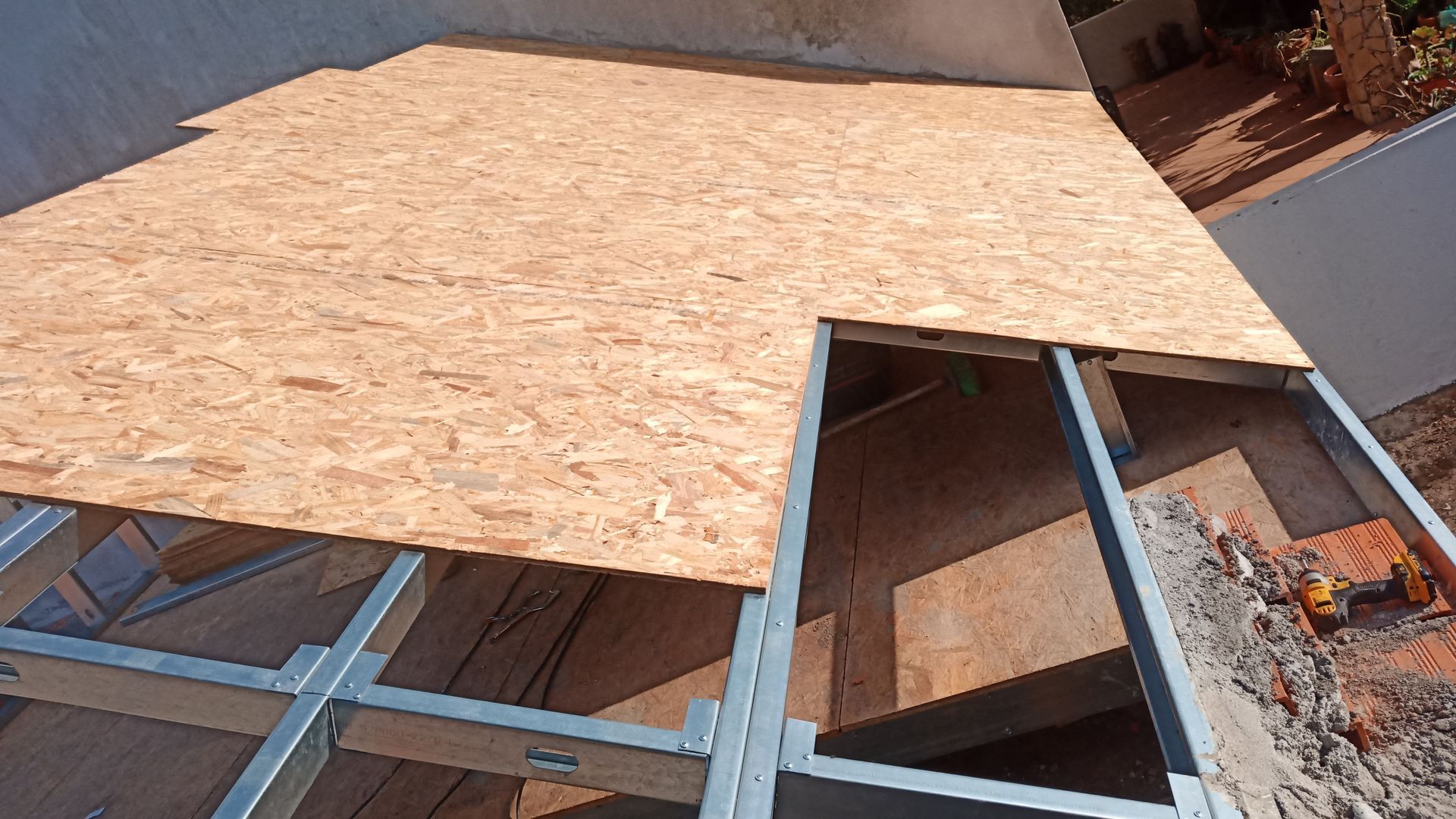 Placa OSB sendo instalada em uma estrutura metálica, possivelmente um telhado ou piso.